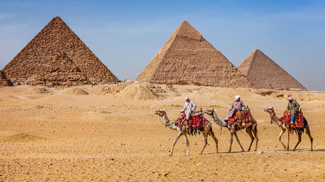 Beduinen auf Kamelen vor den Pyramiden von Gizeh, Ägypten