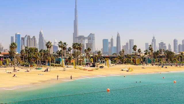 Menschen am Strand von Dubai mit der Skyline im Hintergrund.