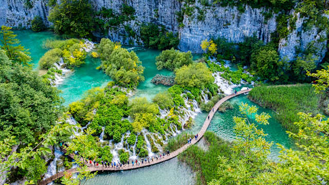 Menschen überqueren eine Brücke im Plitvicer Seen Nationalpark in Kroatien.