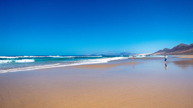 Weitläufiger Strand vor Bergen auf Fuerteventura