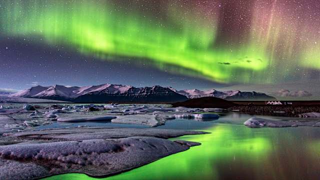 Polarlichter über den schneebedeckten Bergen Islands.
