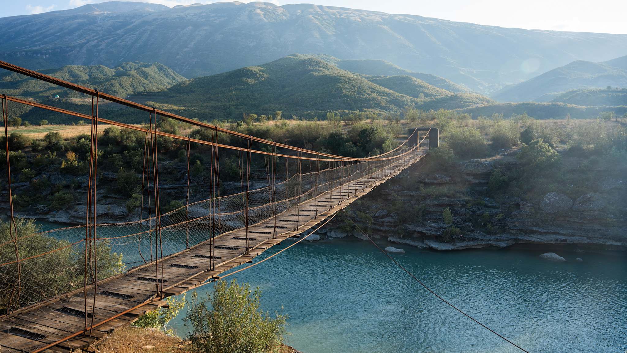 Eine hölzerne Hängebrücke verbindet zwei Landstücke miteinander