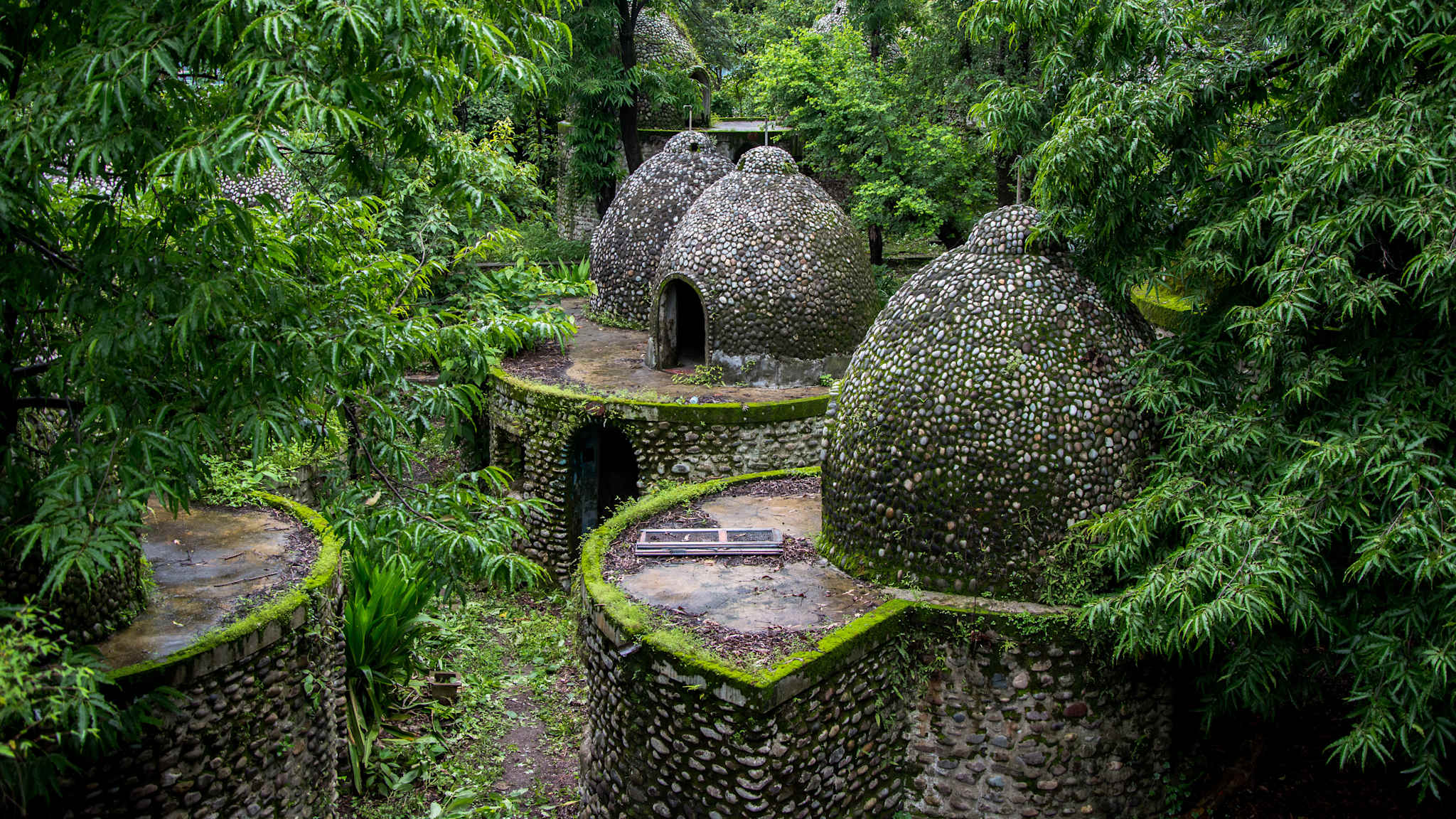 Ashram aus mehreren kleinen, einzelnen runden Steingebäuden im Wald.