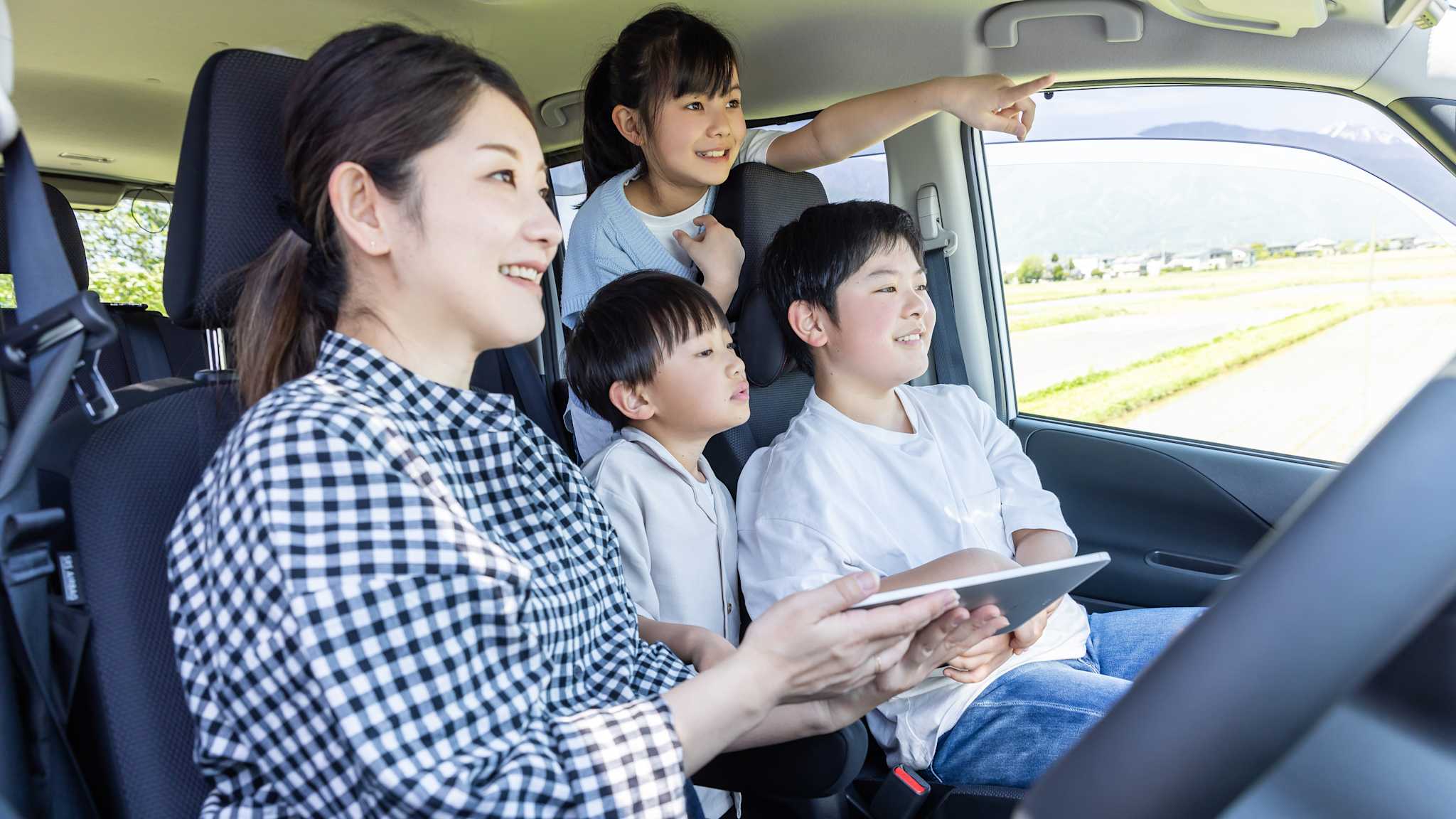 Eine Mutter sitzt mit drei Kindern im Auto.