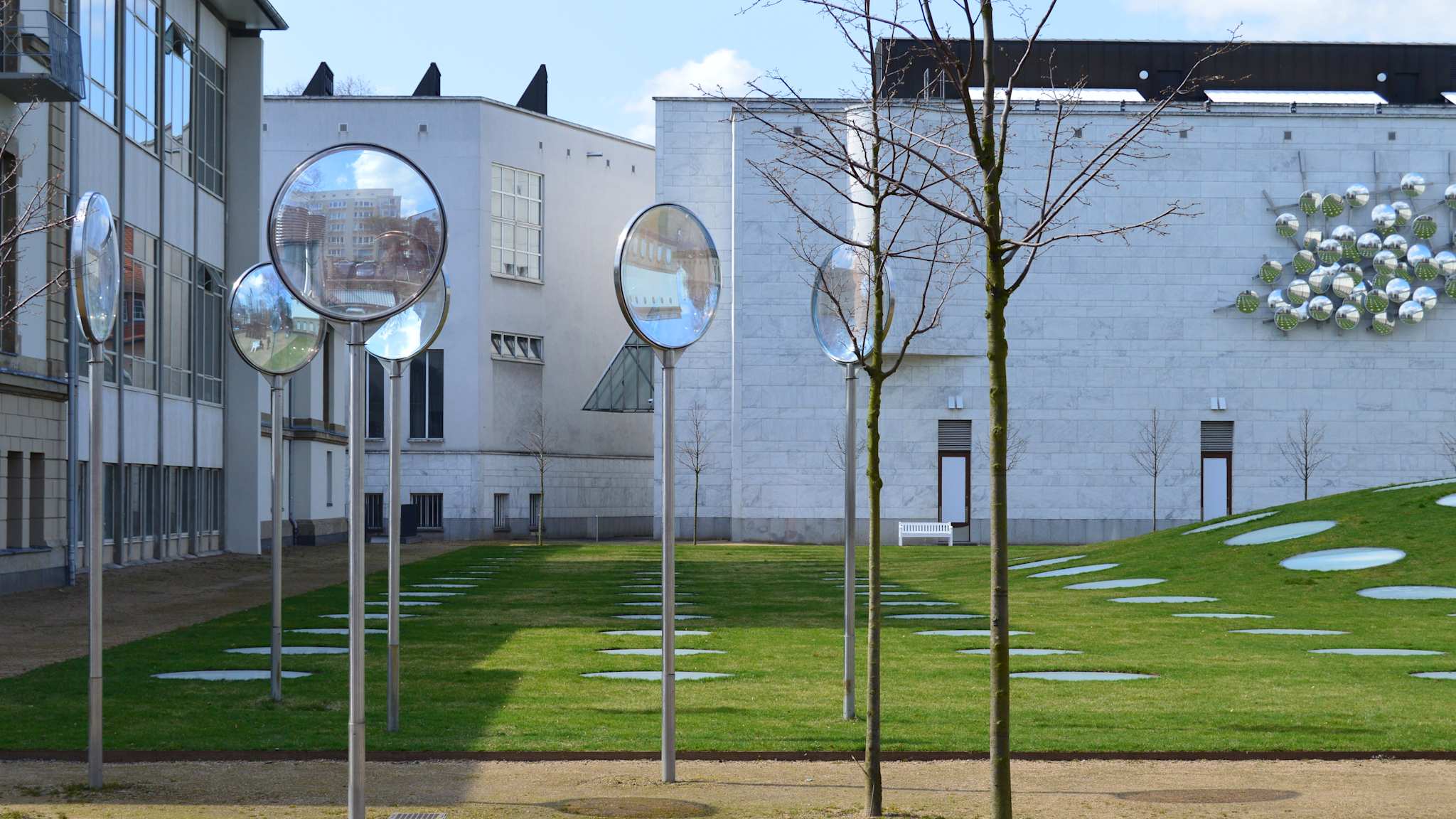 Modernes Gebäude mit grünem Rasen und Spiegelskulpturen