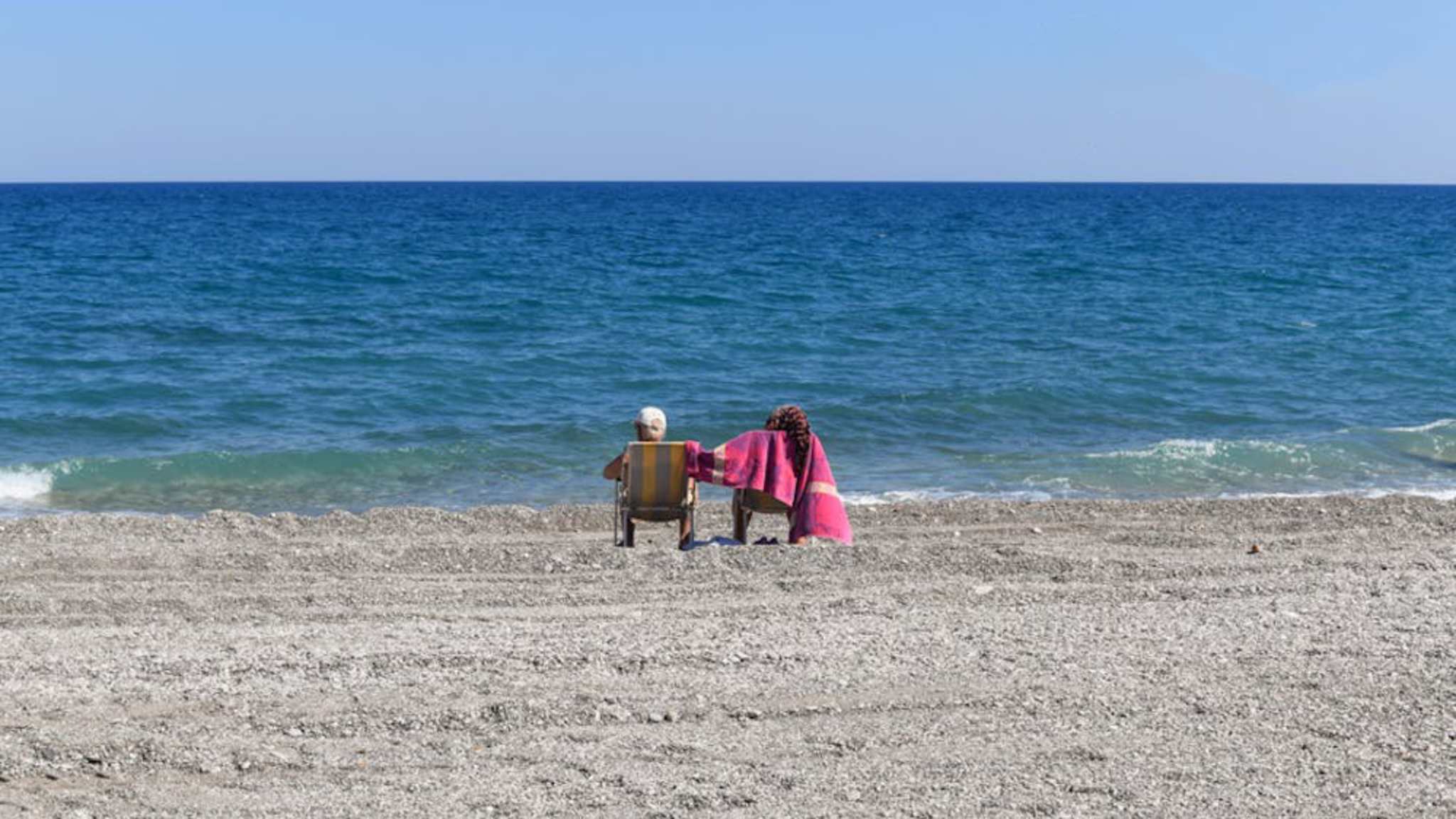 Zwei Menschen in Liegestühlen am Strand
