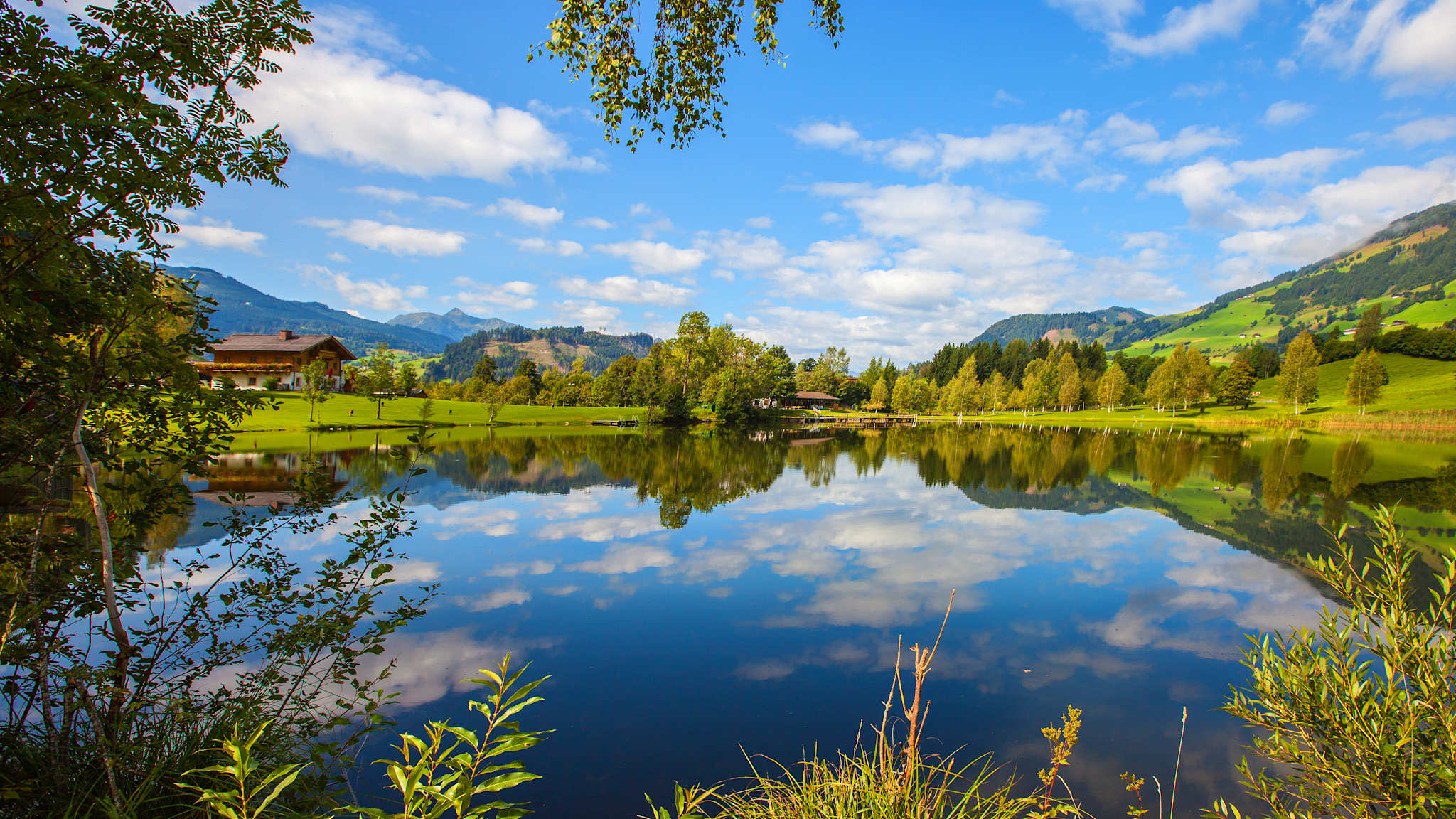 Ausblick auf den Böndlsee in Goldegg im Pongau umgeben von Wiesen, Wäldern und Bergen