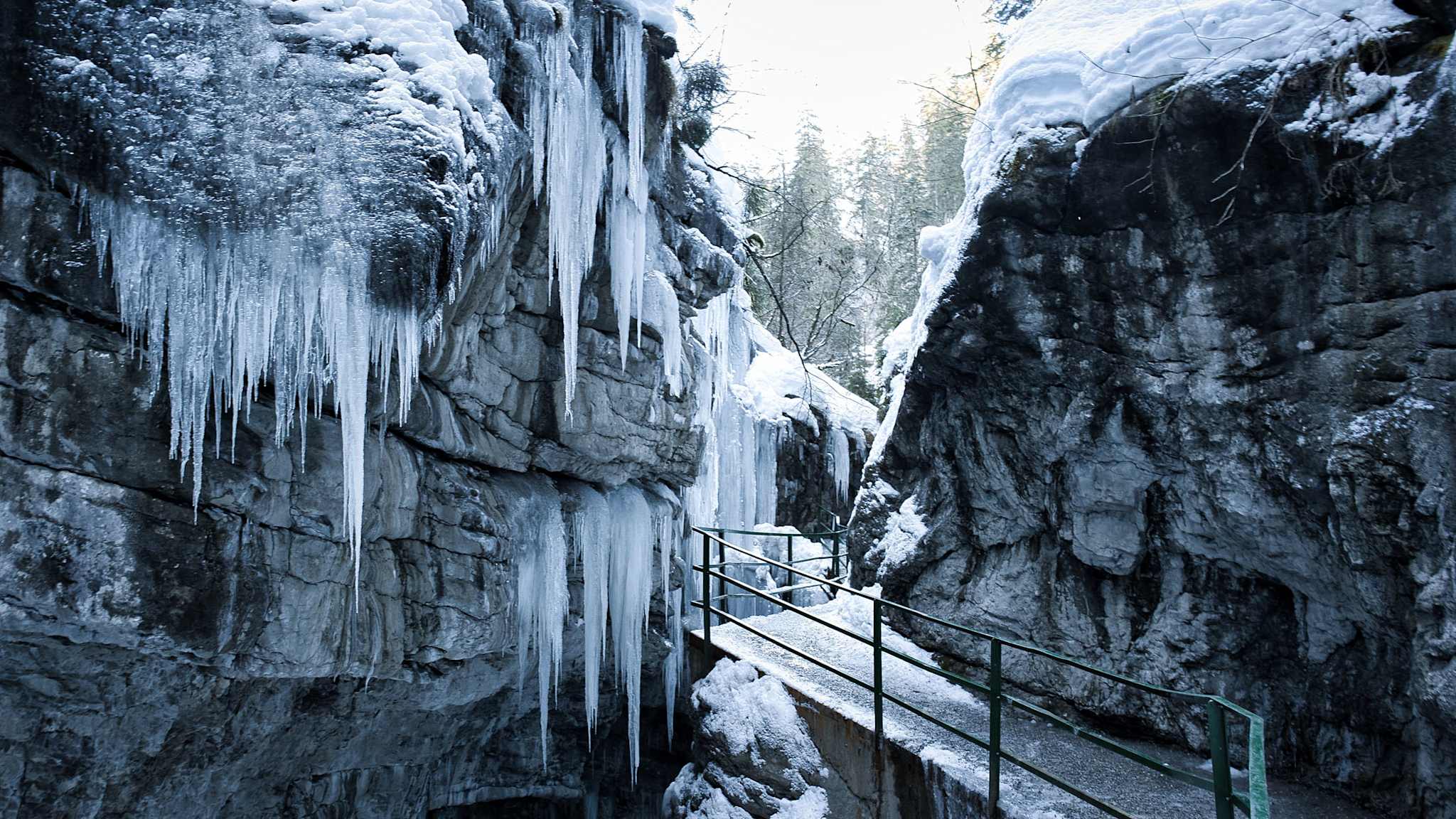 Gefrorene Felsen und Eiszapfen in der Breitachklamm bei Oberstdorf, ein schmaler Steg führt durch die winterliche Schlucht.