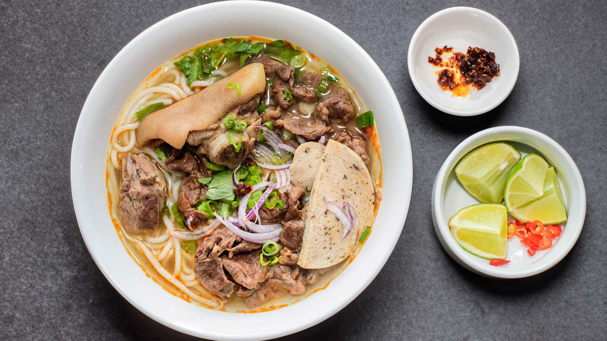 Ein Teller Bún bò Huế: Eine vietnamesische, scharfe Suppe mit Rindfleisch, Schweinebeinscheiben und dicken Reisnudeln.