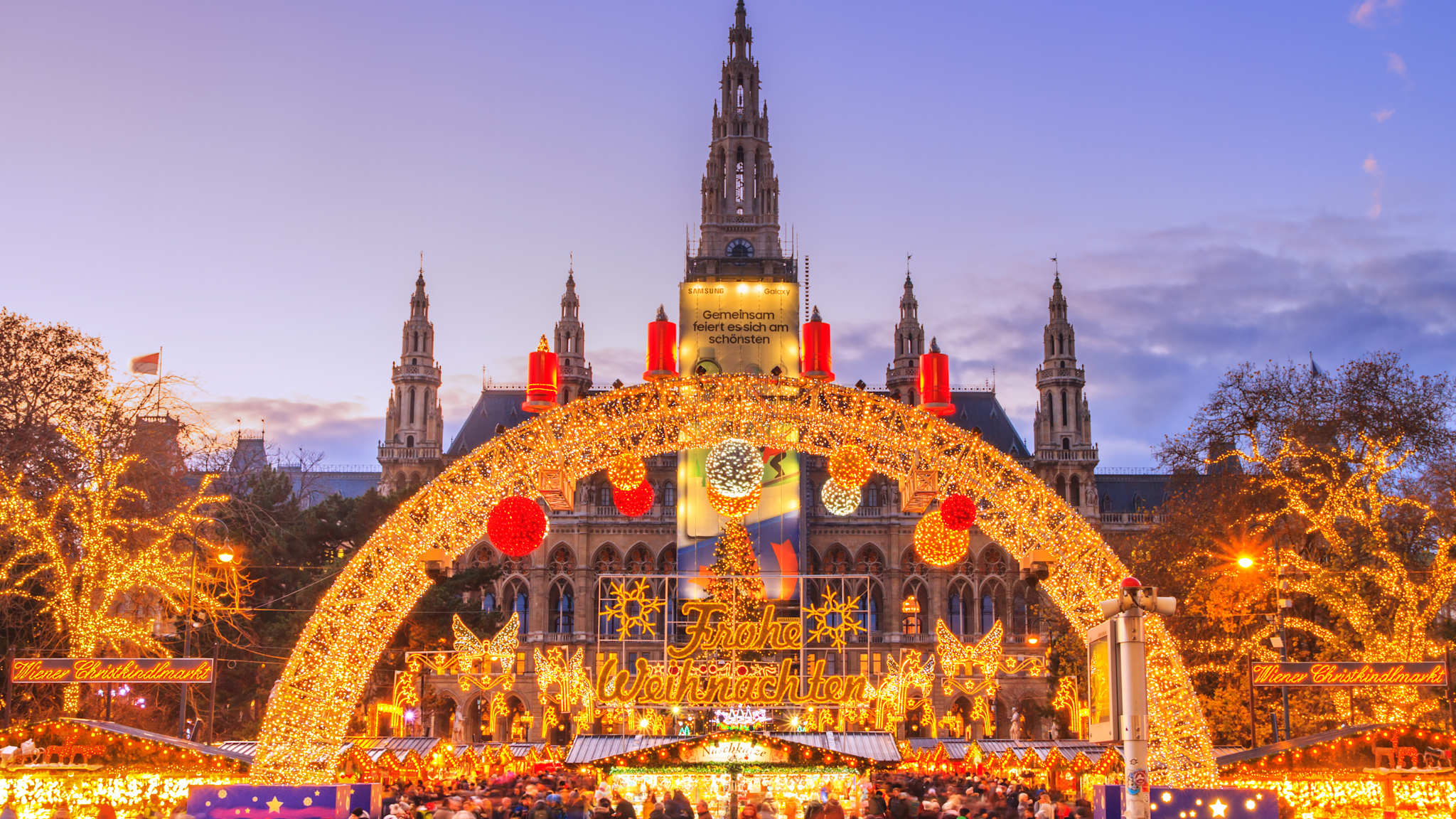 Gold beleuchteter Eingang zum Weihnachtsmarkt auf dem Rathausplatz in Wien.