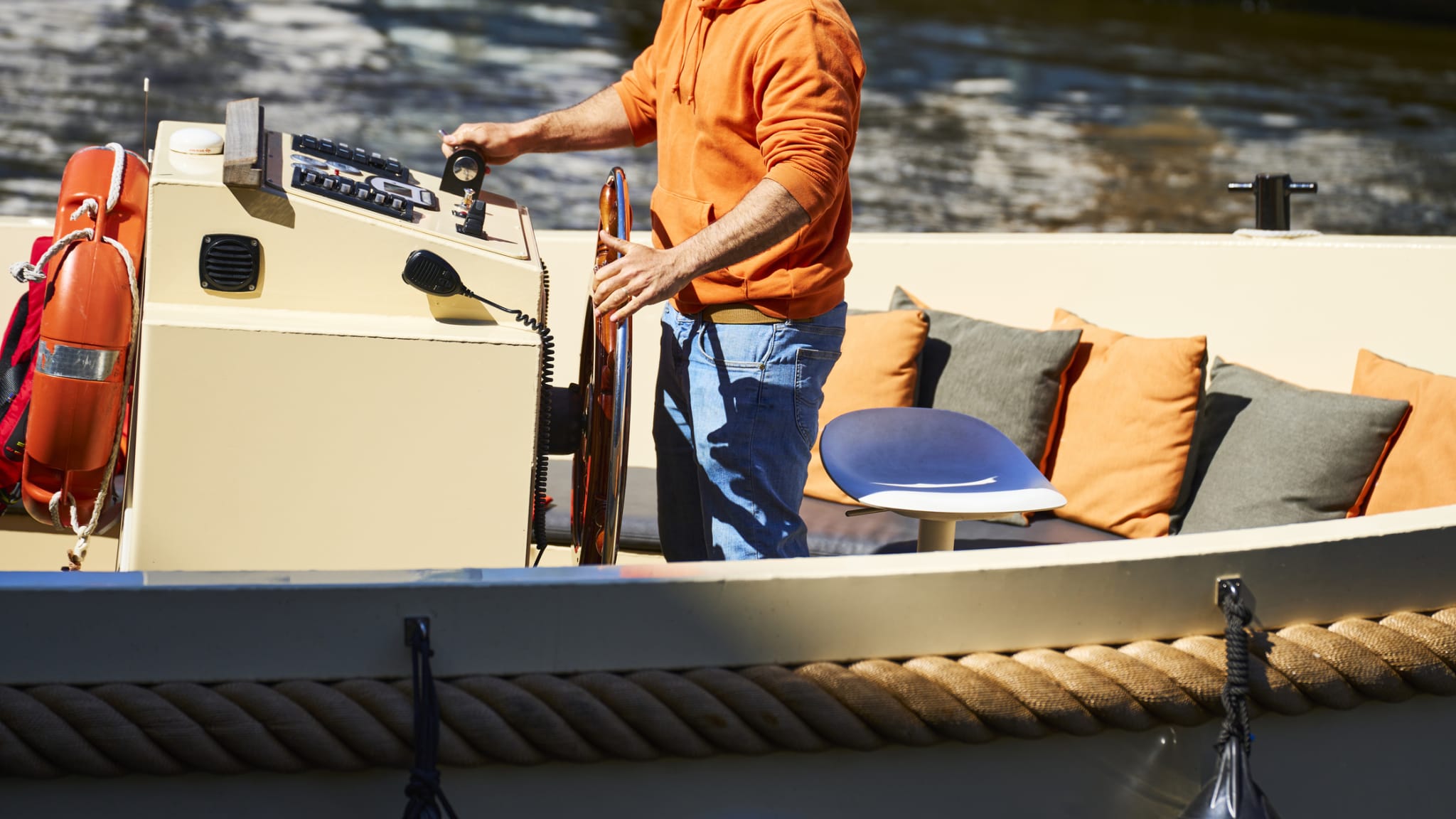 Ein Kapitän fährt sein Boot durch Amsterdam. © aire images/Moment via Getty Images