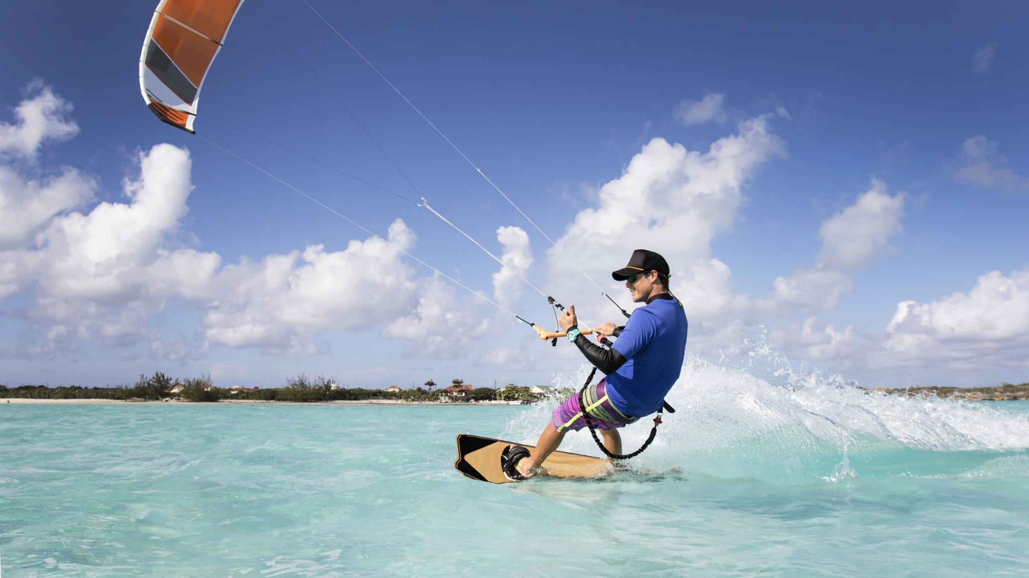 Ein Mann beim Kitesurfen in der Karibik und Wellen Spritzen nach oben © iStock.com/JMichl