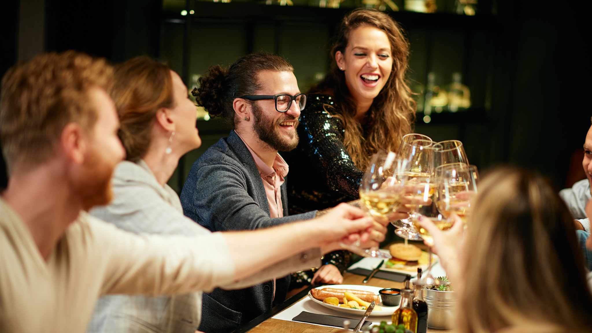 Eine Gruppe FreundInnen stoßen an einem Restauranttisch an