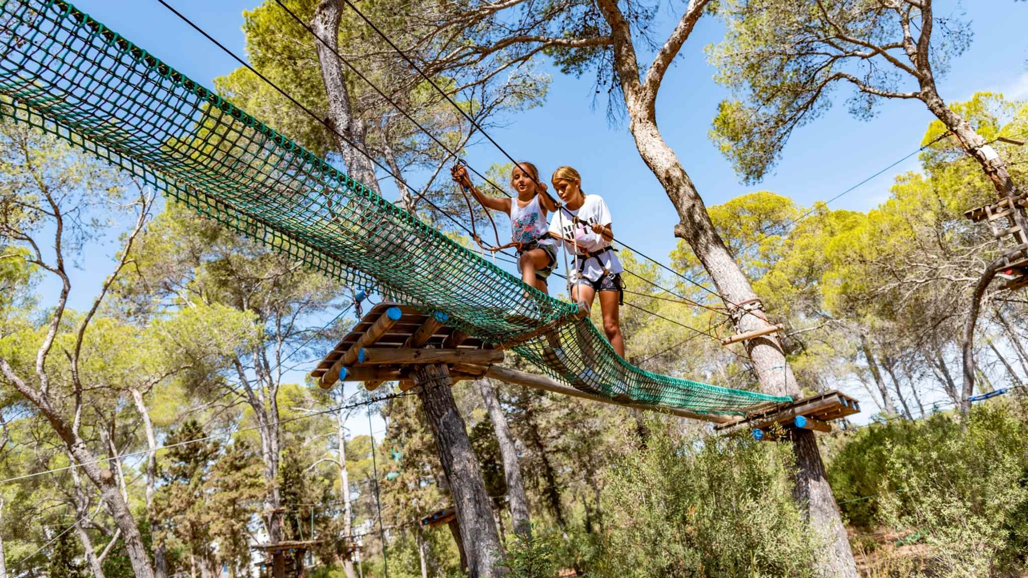 Zwei Kindern klettern in einem Kletterwald auf Ibiza
