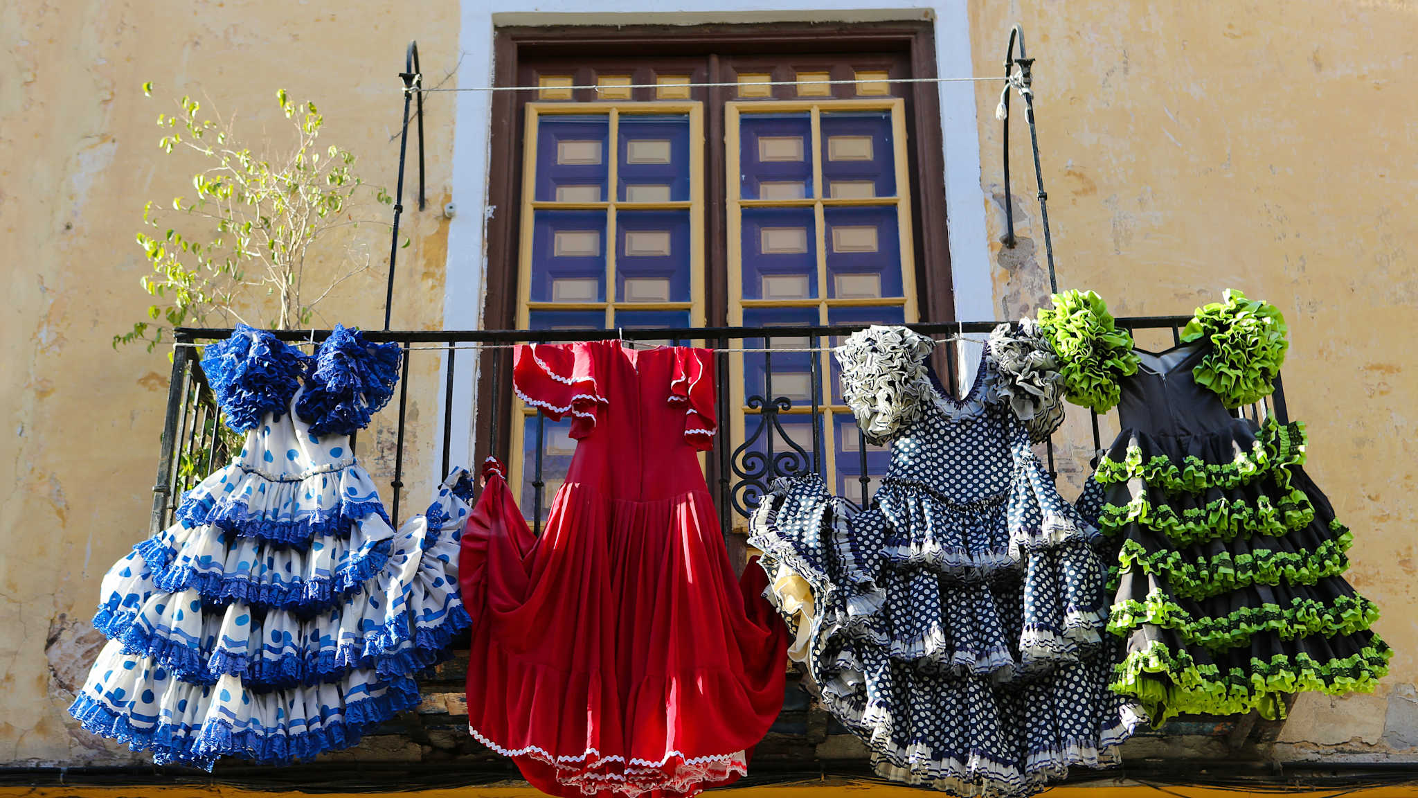 Vier Flamencokleider hängen am Geländer eines Balkons