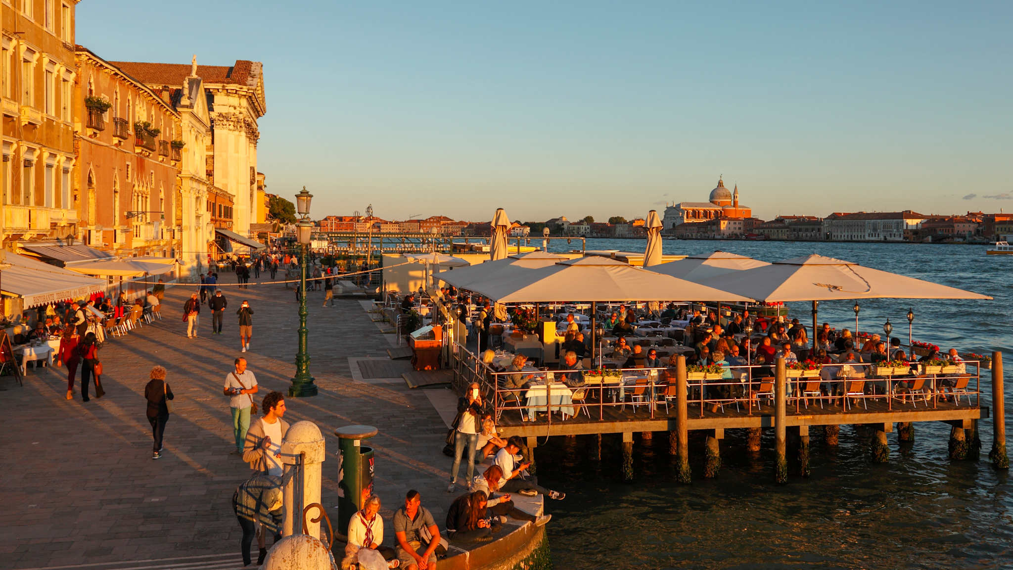 Blick entlang der Promenade Fondamenta Zattere am Wasser in Venedig mit Sitzplätzen von Restaurants über dem Wasser.