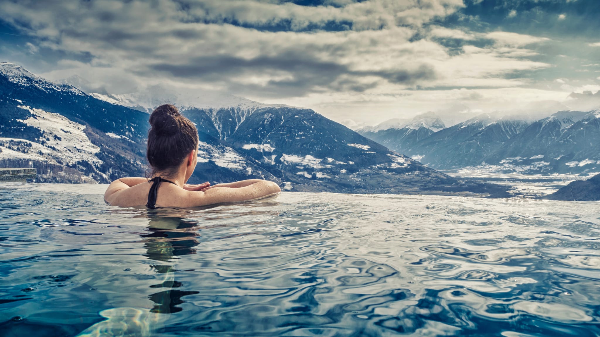 Frau schaut über den Rand eines-Pools auf die Berge © iStock.com/unit-d