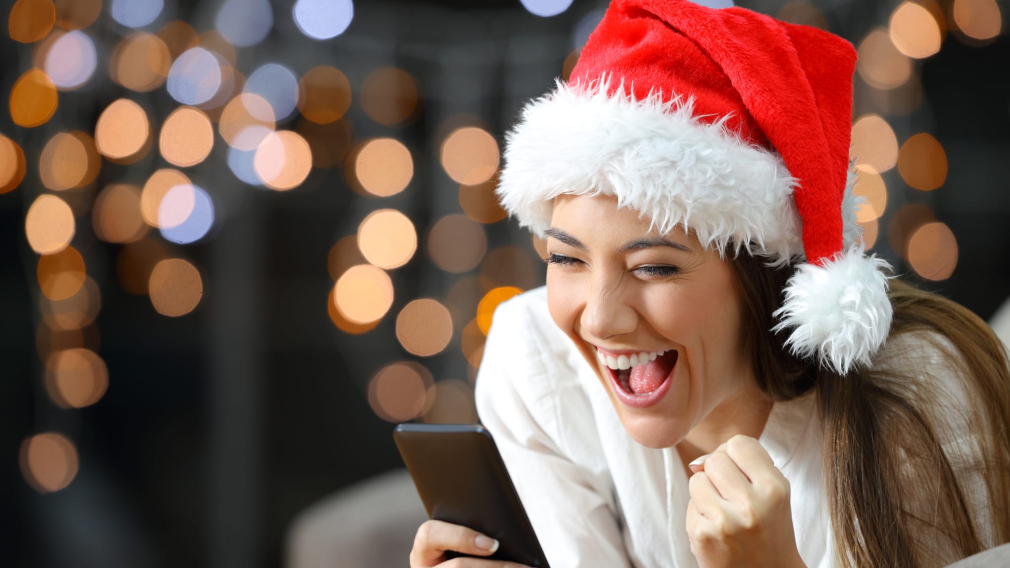 Frau verfolgt Weihnachtslotterie © AntonioGuillem/iStock / Getty Images Plus via Getty Images