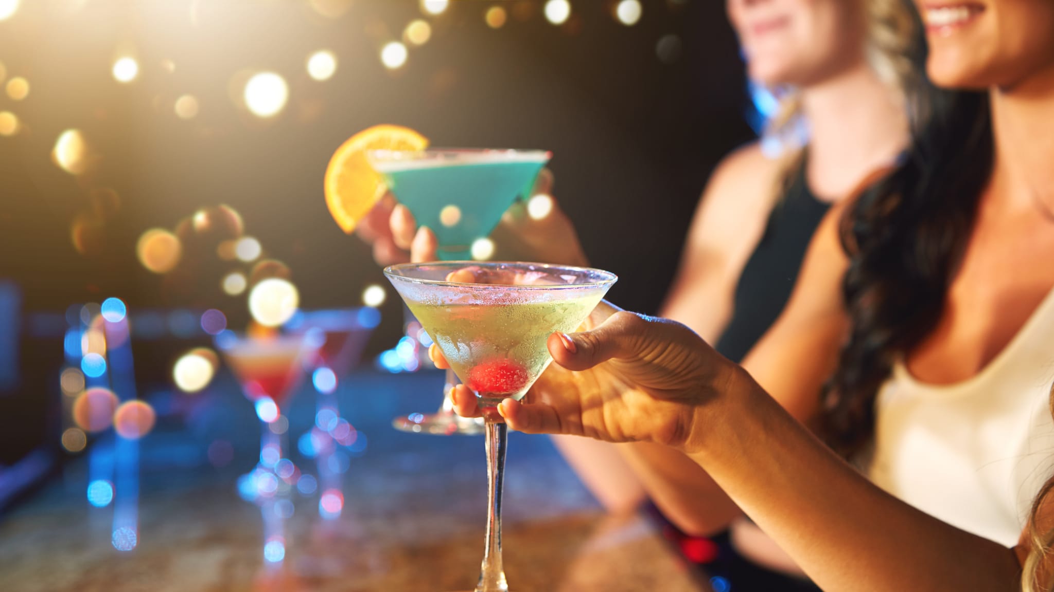 Frauen trinken bunte Cocktails in einem Nachtclub. © gradyreese/iStock / Getty Images Plus via Getty Images