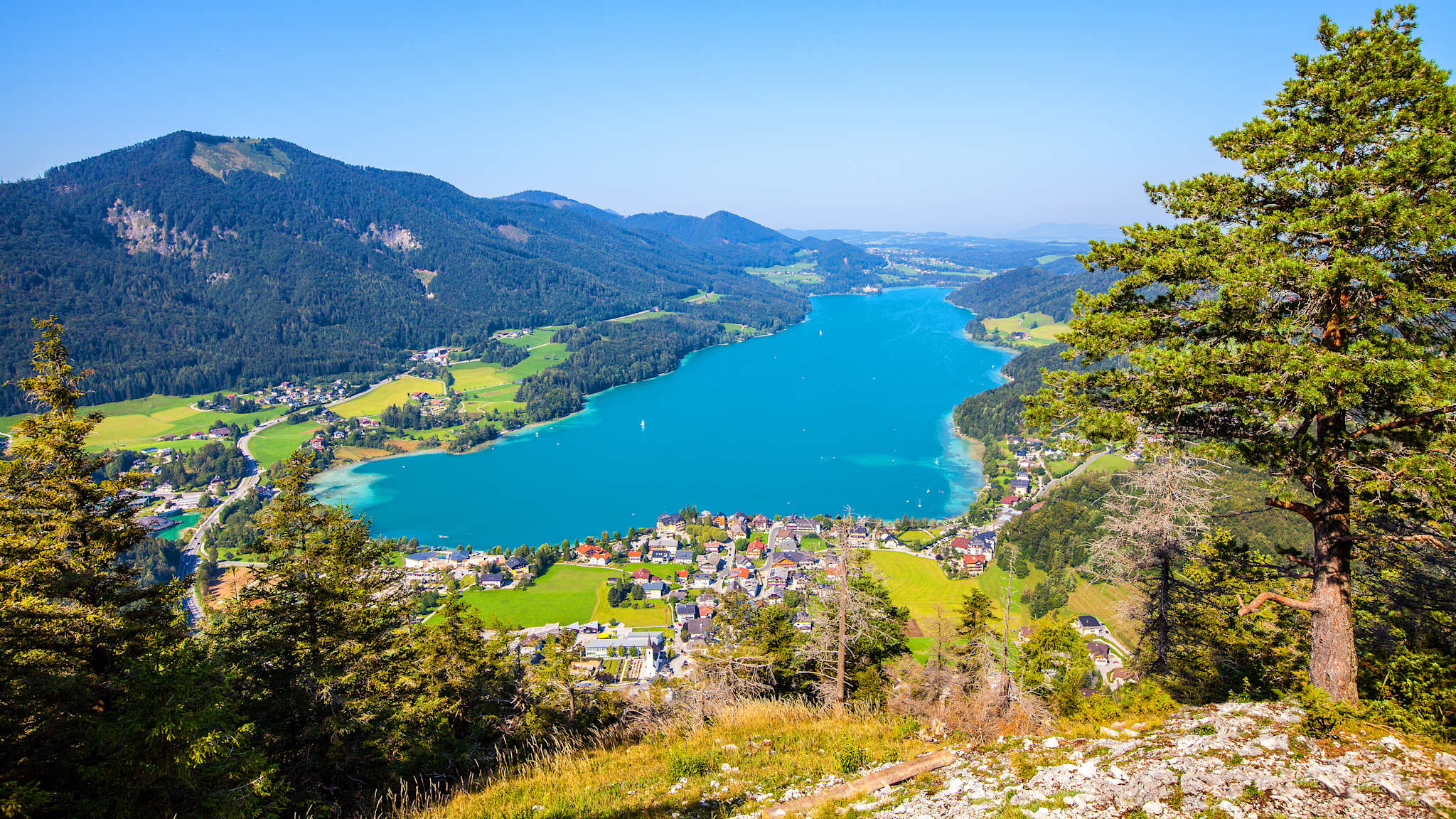 Blick aus der Luft auf einen länglichen See und Berge
