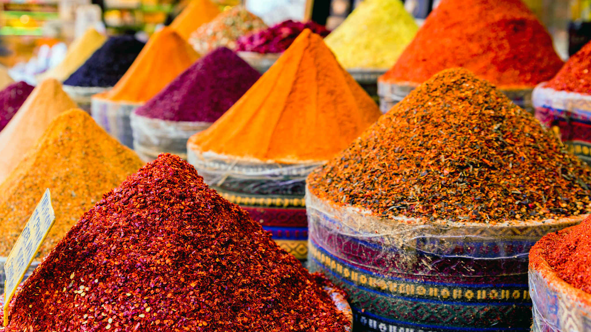 Bunte Gewürze in bunt gestreiften großen Gefäßen auf einem Markttisch in Istanbul.