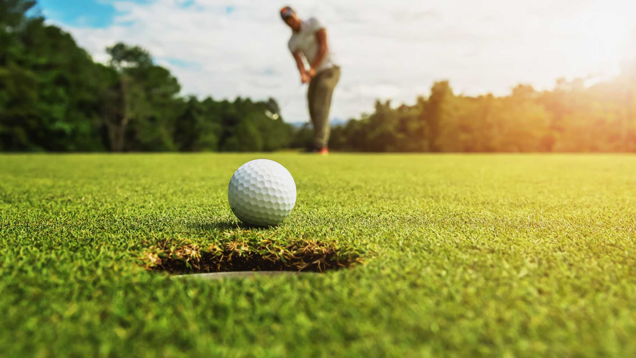 Golfer beim Putt – der Ball kurz vor dem Loch