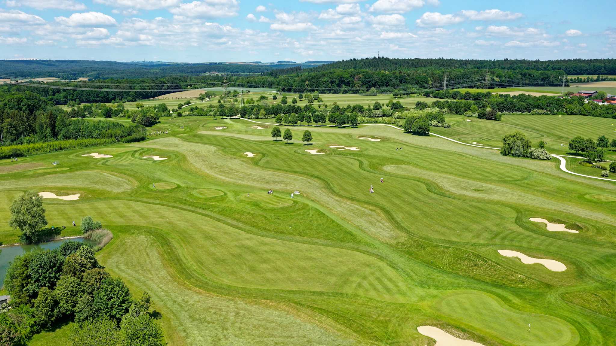 Luftaufnahme eines Golfplatzes, der von waldreichen Gebieten umgeben ist
