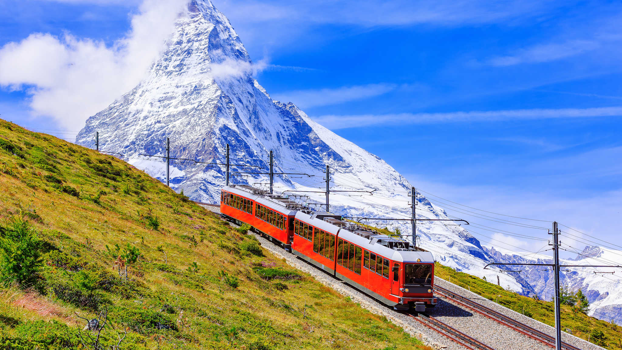 Eine rote S-Bahn fährt einen Berg hinauf. Gegenüber steht der Berg Zermatt.