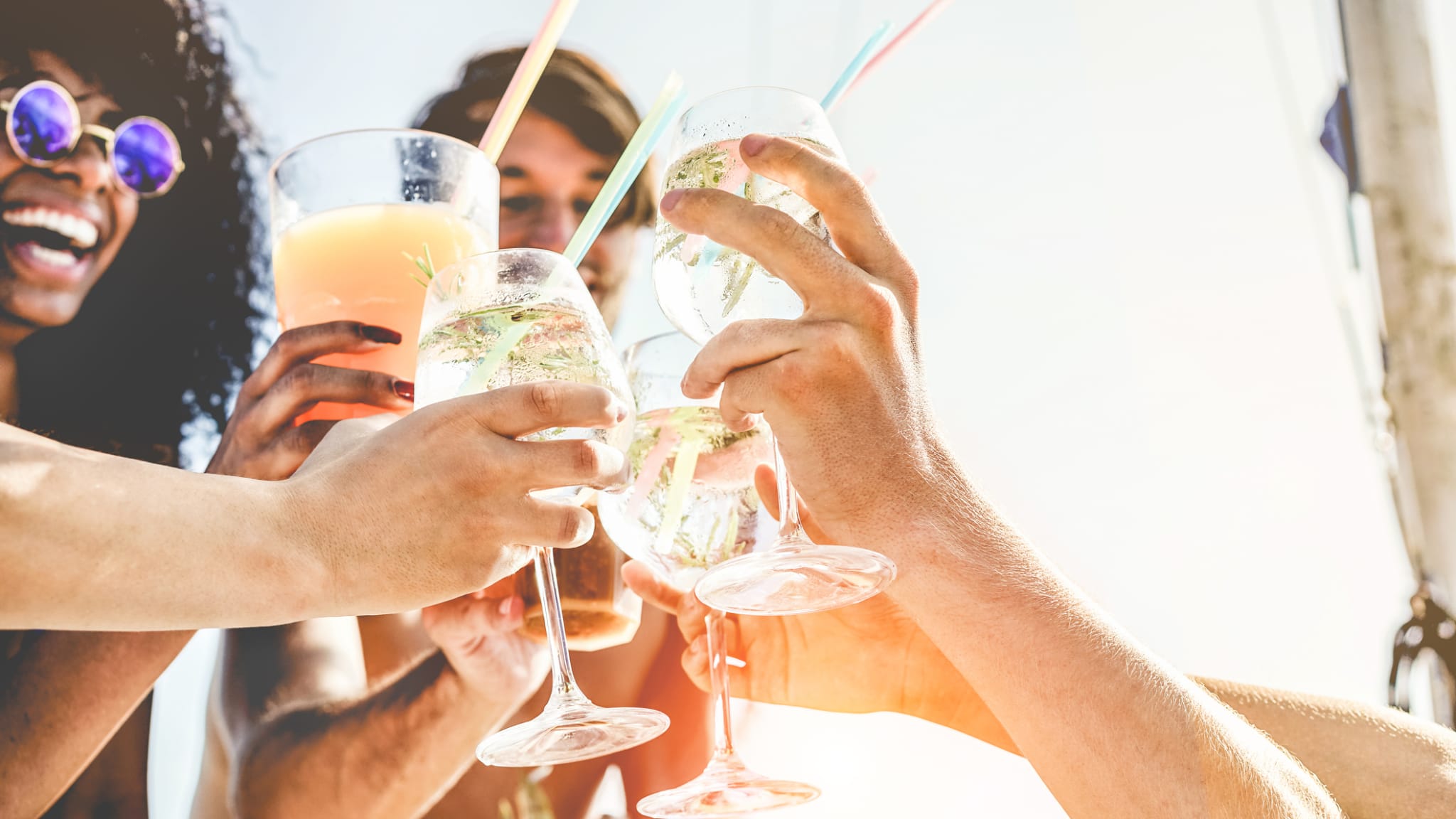 Gruppe von Freunden stoßen mit tropischen Cocktails an © iStock.com/DisobeyArt