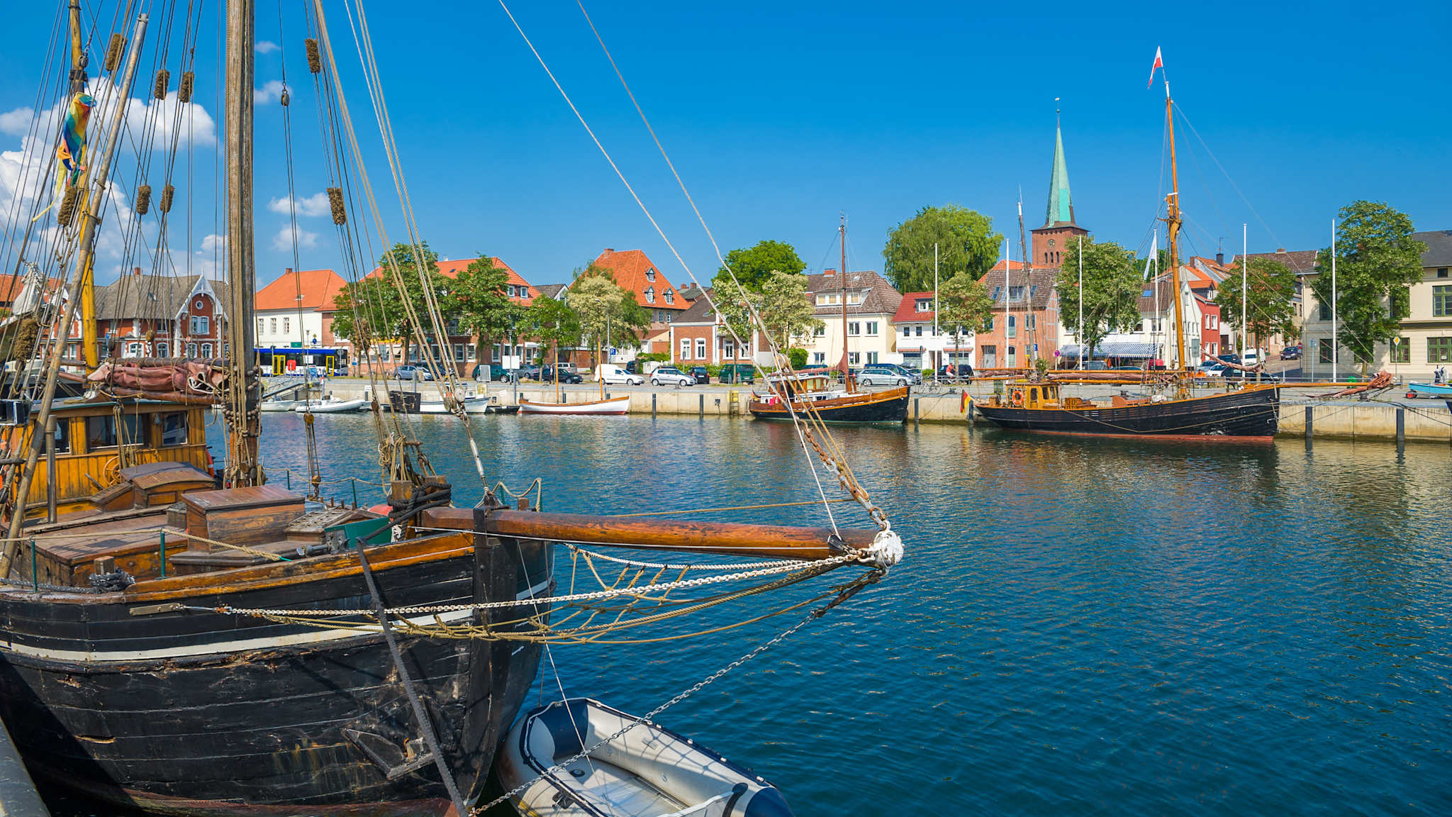 Blick auf den kleinen Hafen von Neustadt in Holstein mit alten Kähnen an den Seiten.