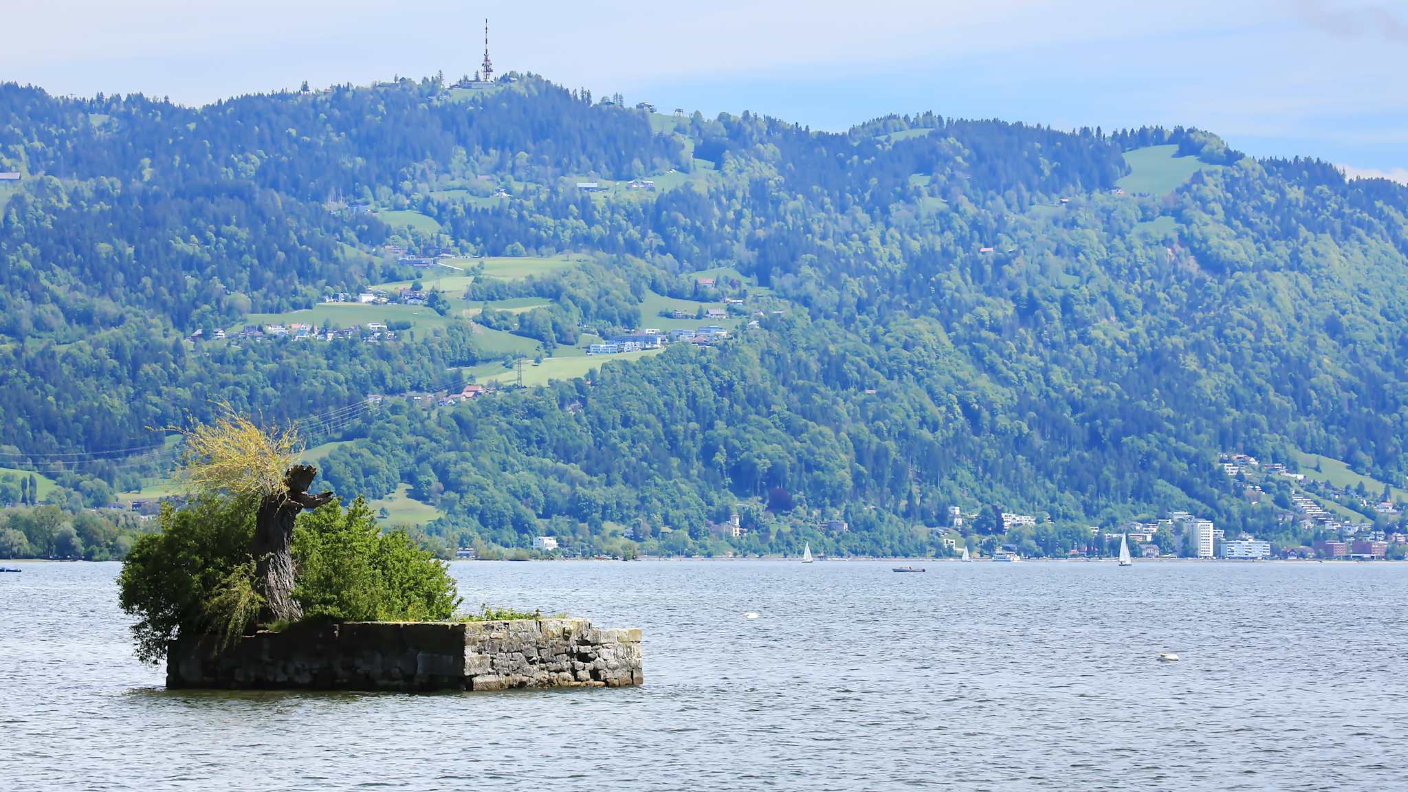 Winzige, aufgeschüttete Insel, grüne Berge im Hintergrund