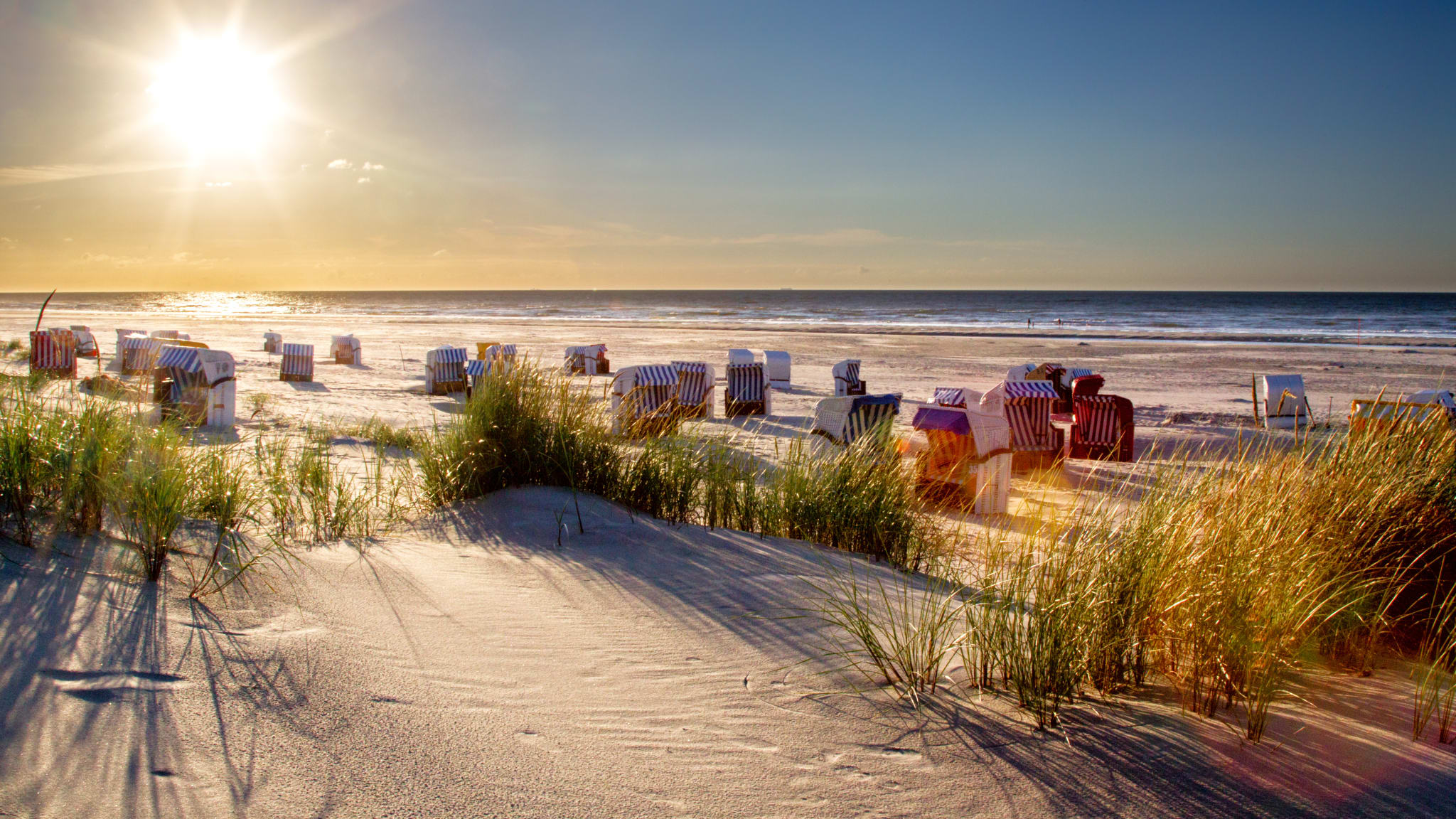 Sonnenuntergang und Strandkörbe auf Juist, ostfriesische Inseln im niedersächsischen Wattenmeer.