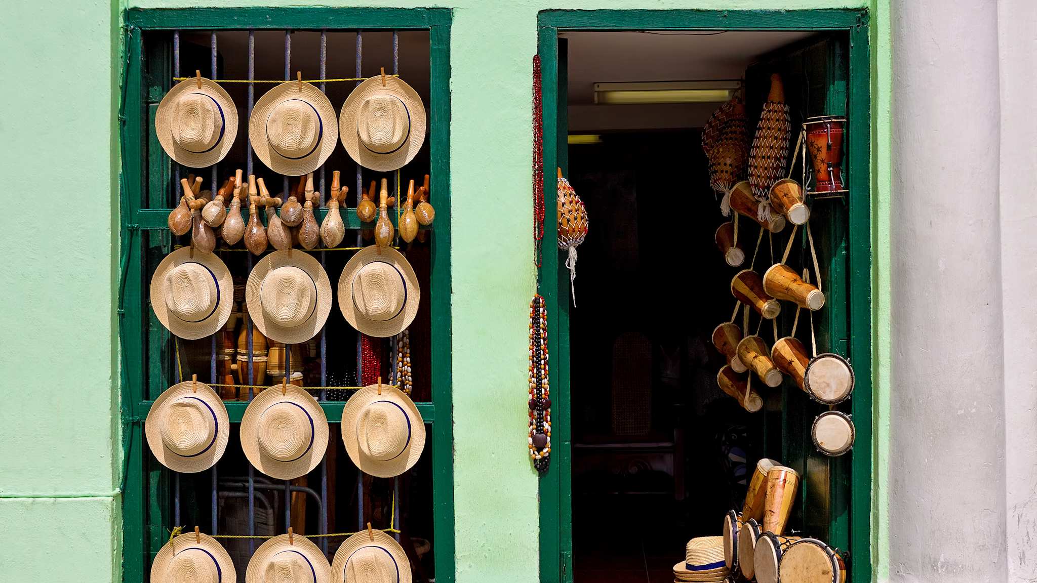 Grüne Geschäftsfront von einem Souvenirladen in Old Havana, das Hüte, Trommeln und andere Instrumente verkauft.