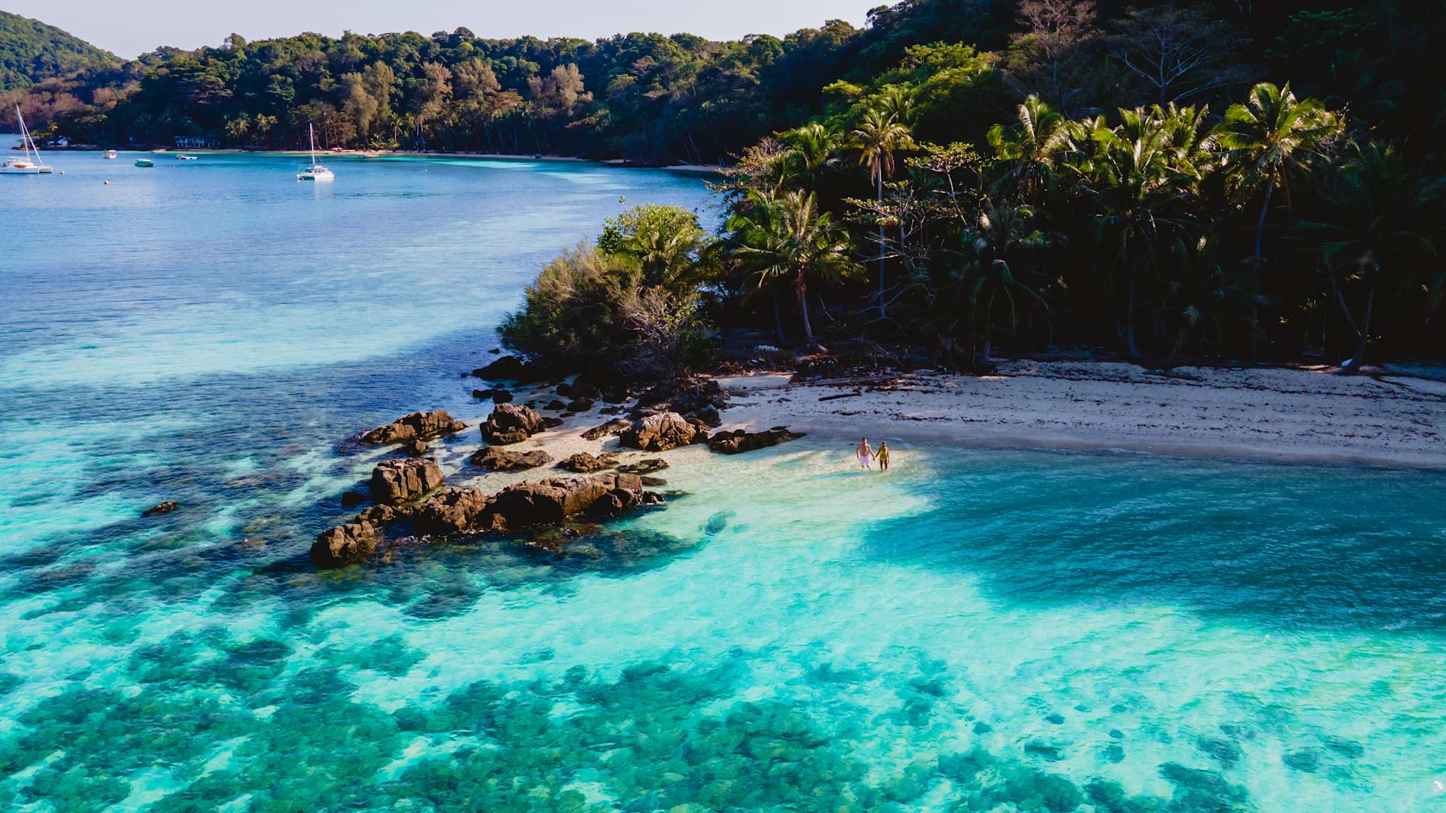 Ausblick vom türkisfarbenen Meer aus auf die Strände der Insel Koh Wai mit Palmenwald.