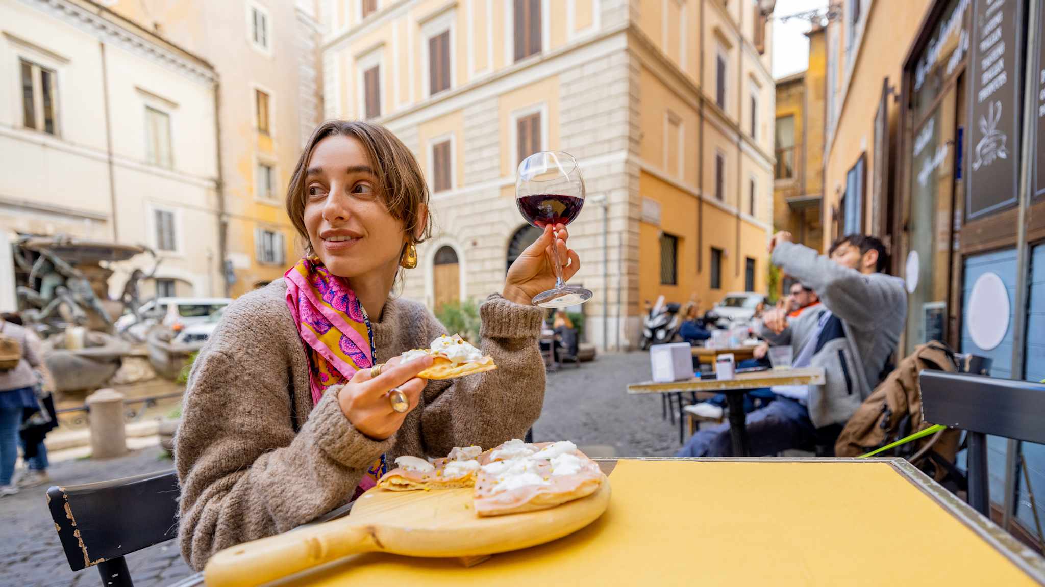 Frau mit Pizza und Weinglas sitzt an einem Tisch in der Altstadt