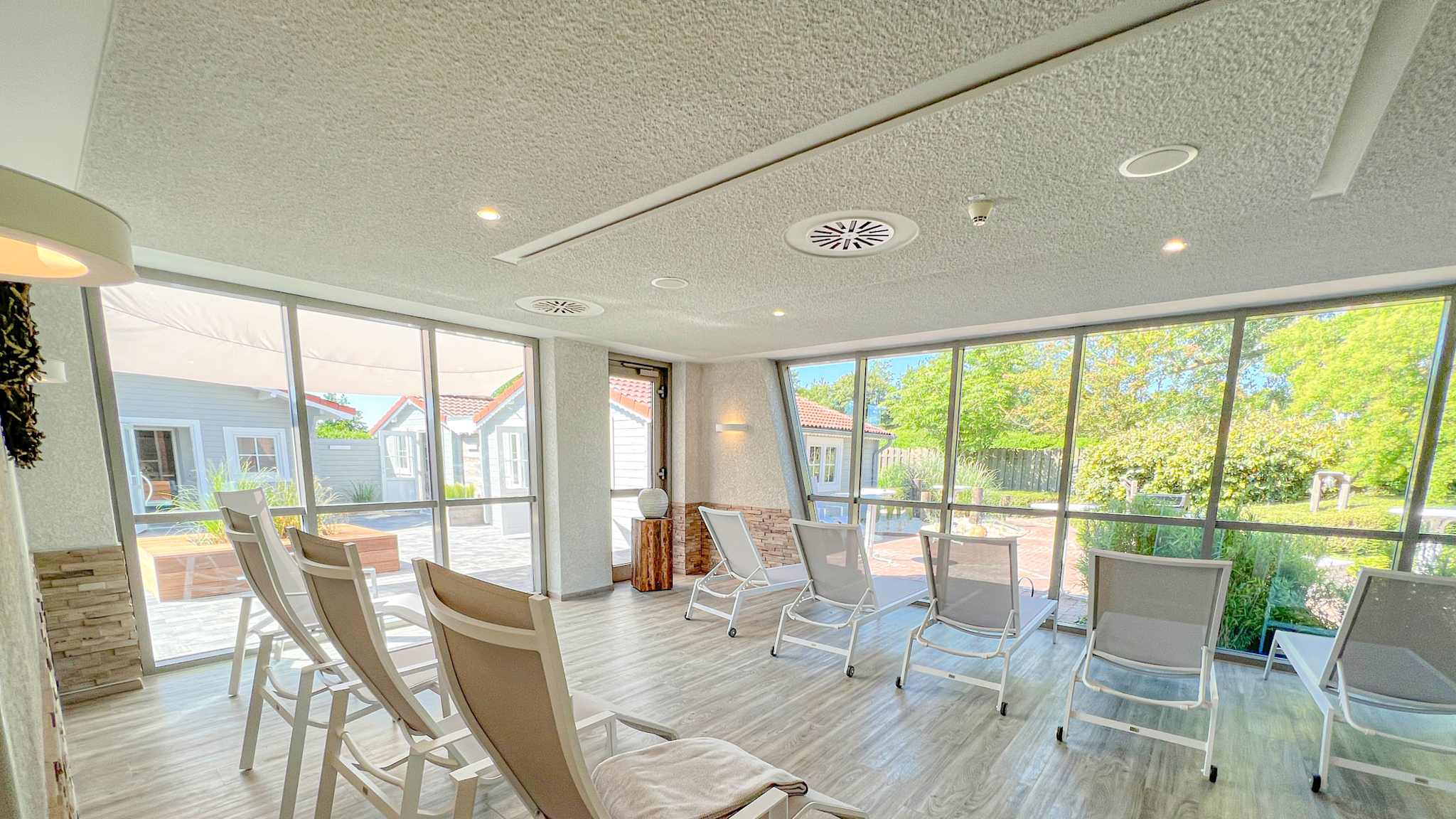 Moderner, lichtdurchfluteter Ruheraum mit bequemen Relaxliegen, großen Fensterfronten und Blick auf die gepflegte Gartenanlage der Friesland-Therme Horumersiel.
