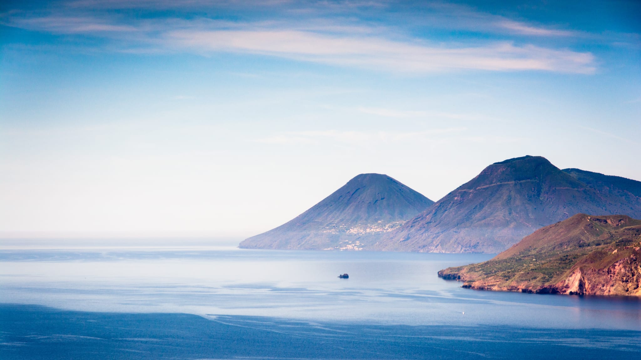 Blick über das Wasser auf zwei vulkanische Inseln