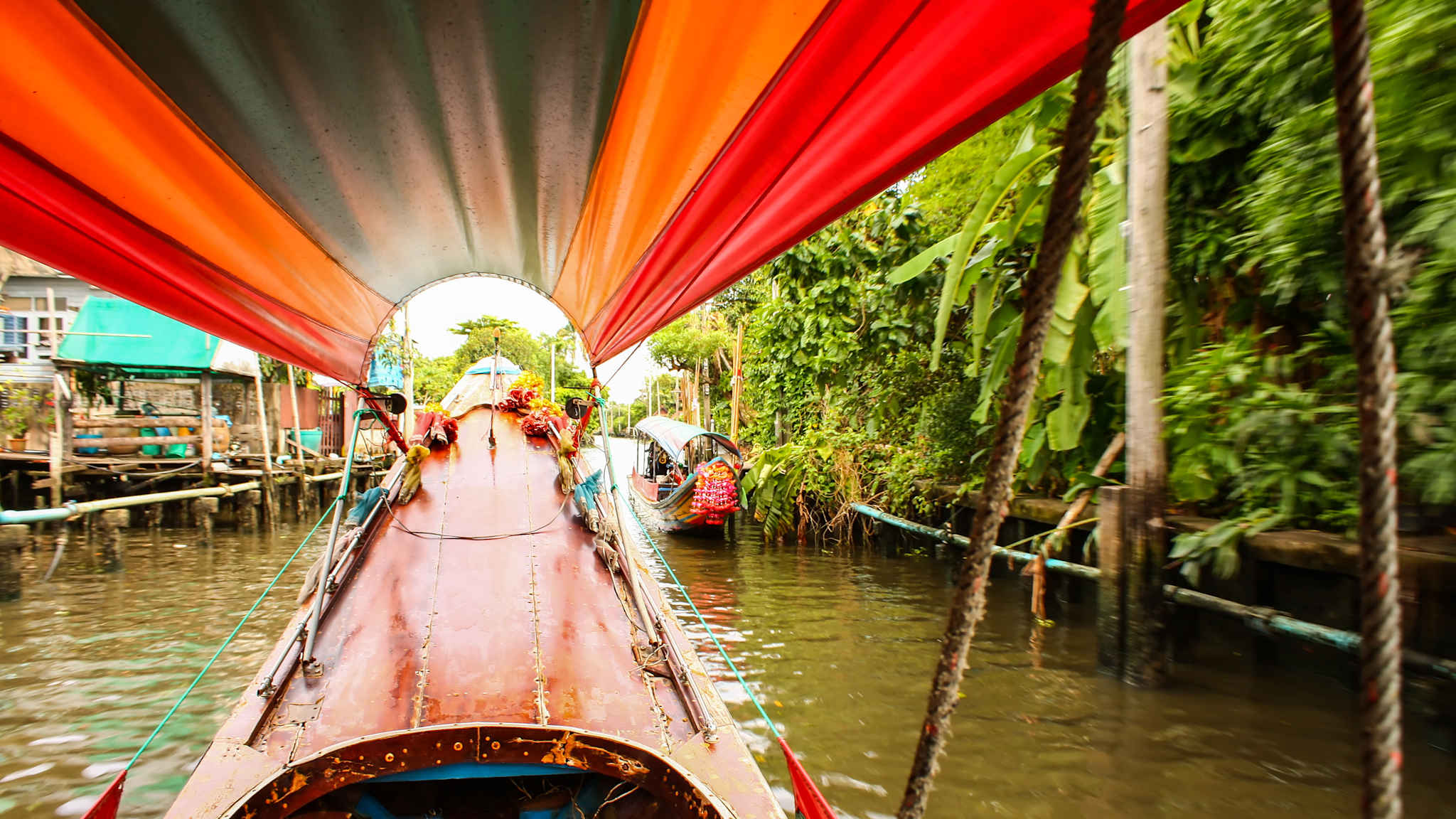 Der Blick aus einem Longtailboot heraus auf den vorderen Teil von Boot und Dach auf dem Chao Phraya Fluss in Bangkok.