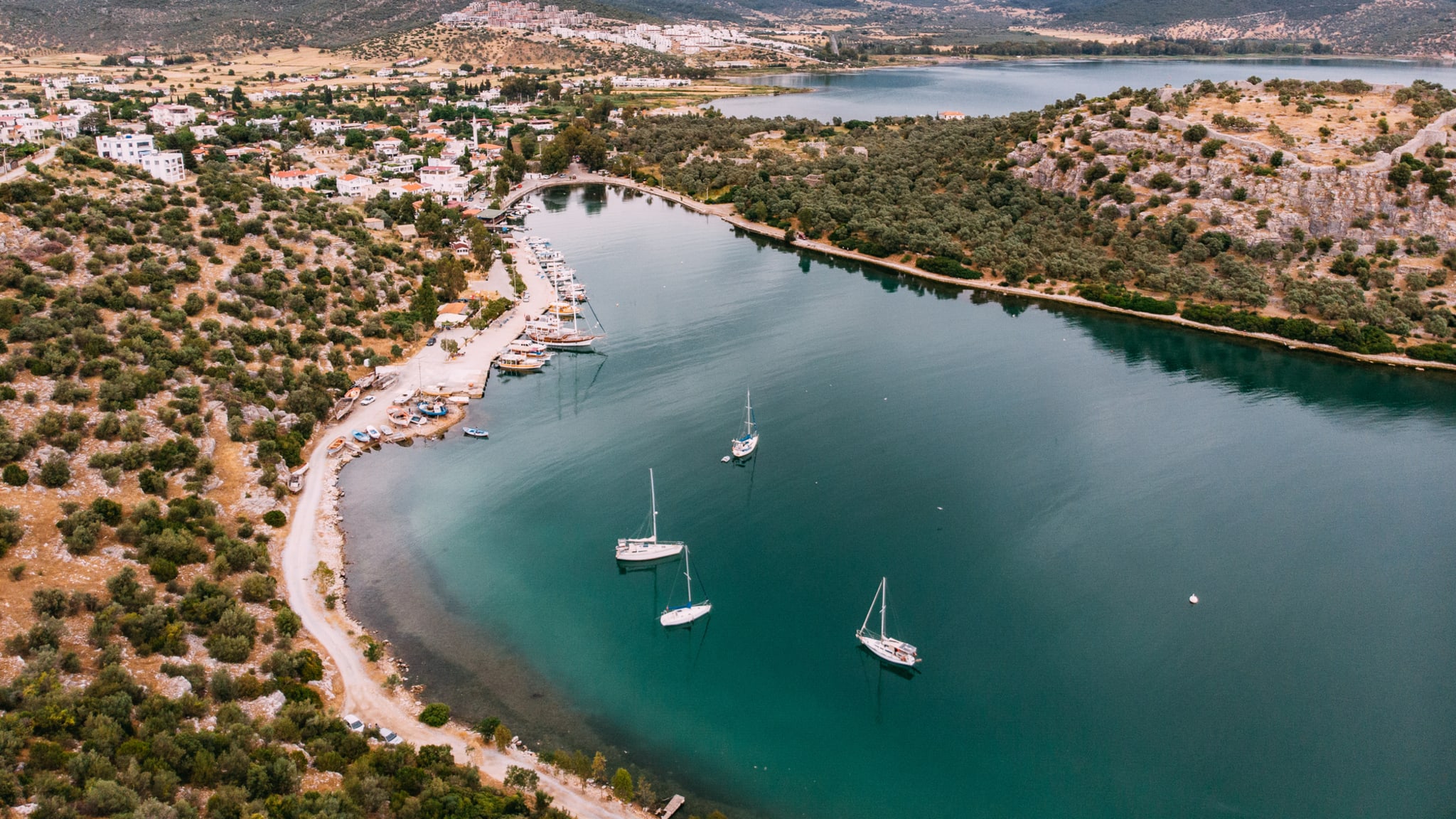 Luftaufnahme einer kleinen Küstenstadt und Segelbooten im Meer © iStock.com/AegeanBlue