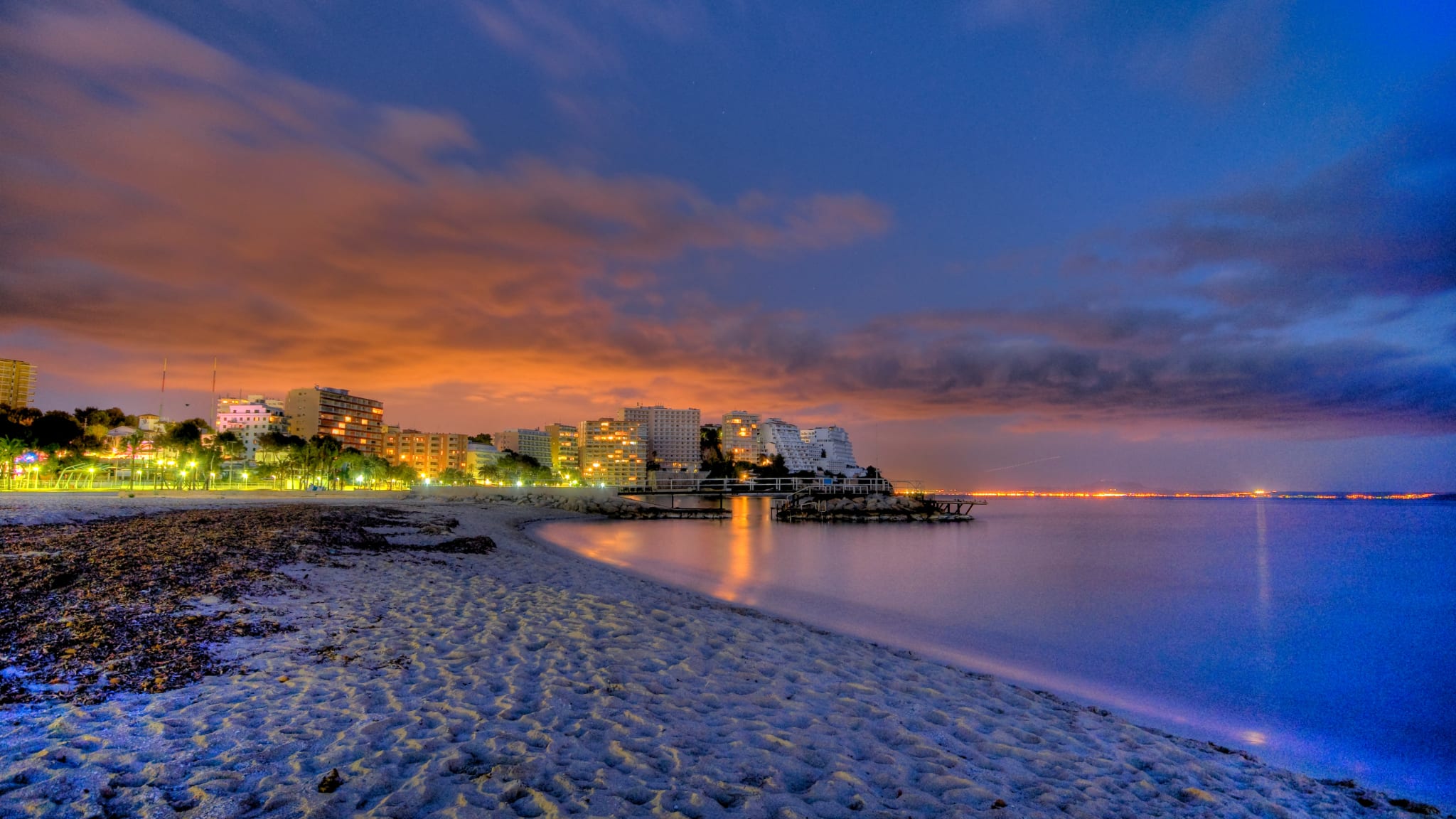 Ein Strand mit einer neonbeleuchteten Stadt im Hintergrund