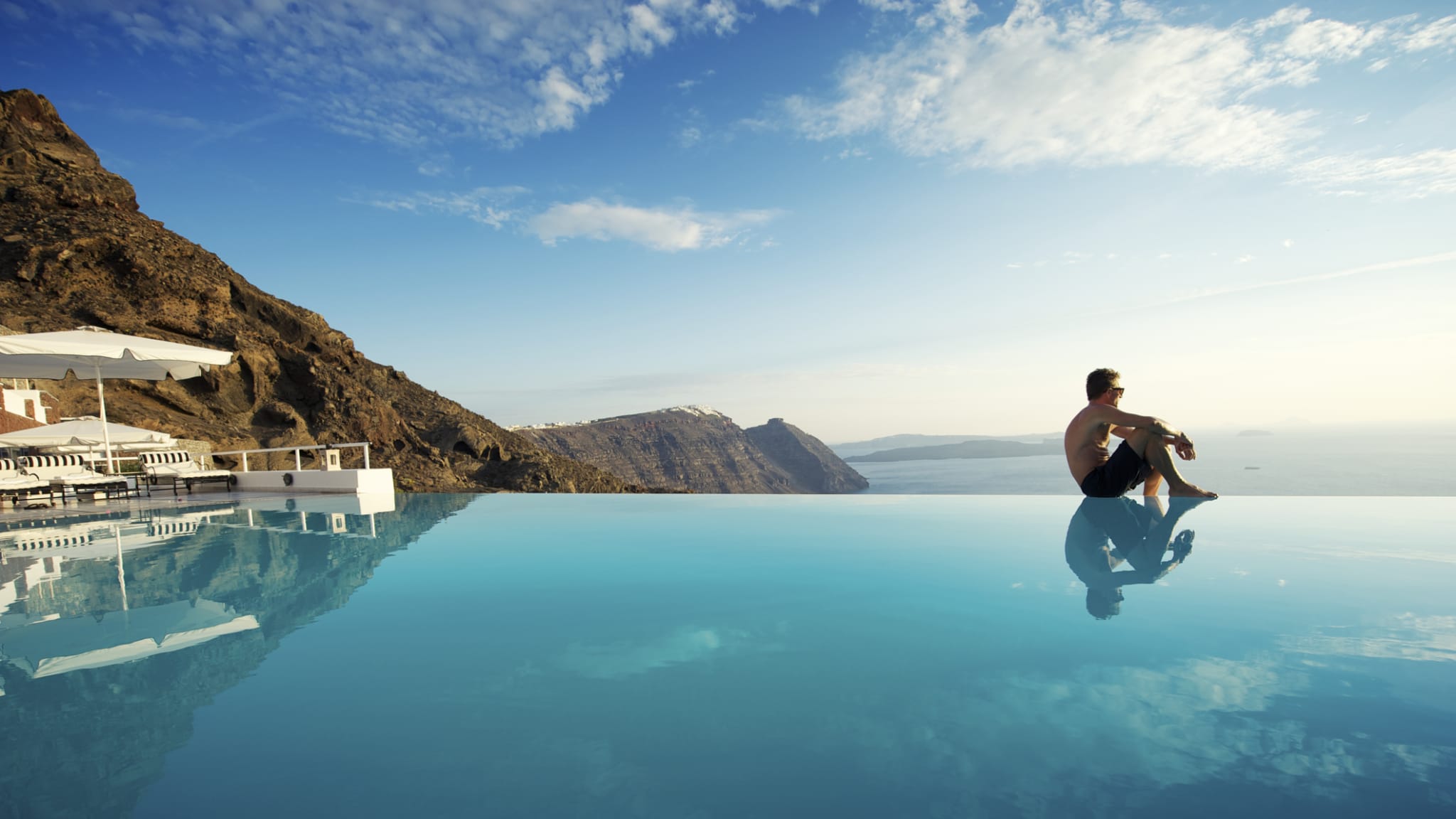 Mann an einem Pool auf Santorini © PeskyMonkey/iStock / Getty Images Plus via Getty Images