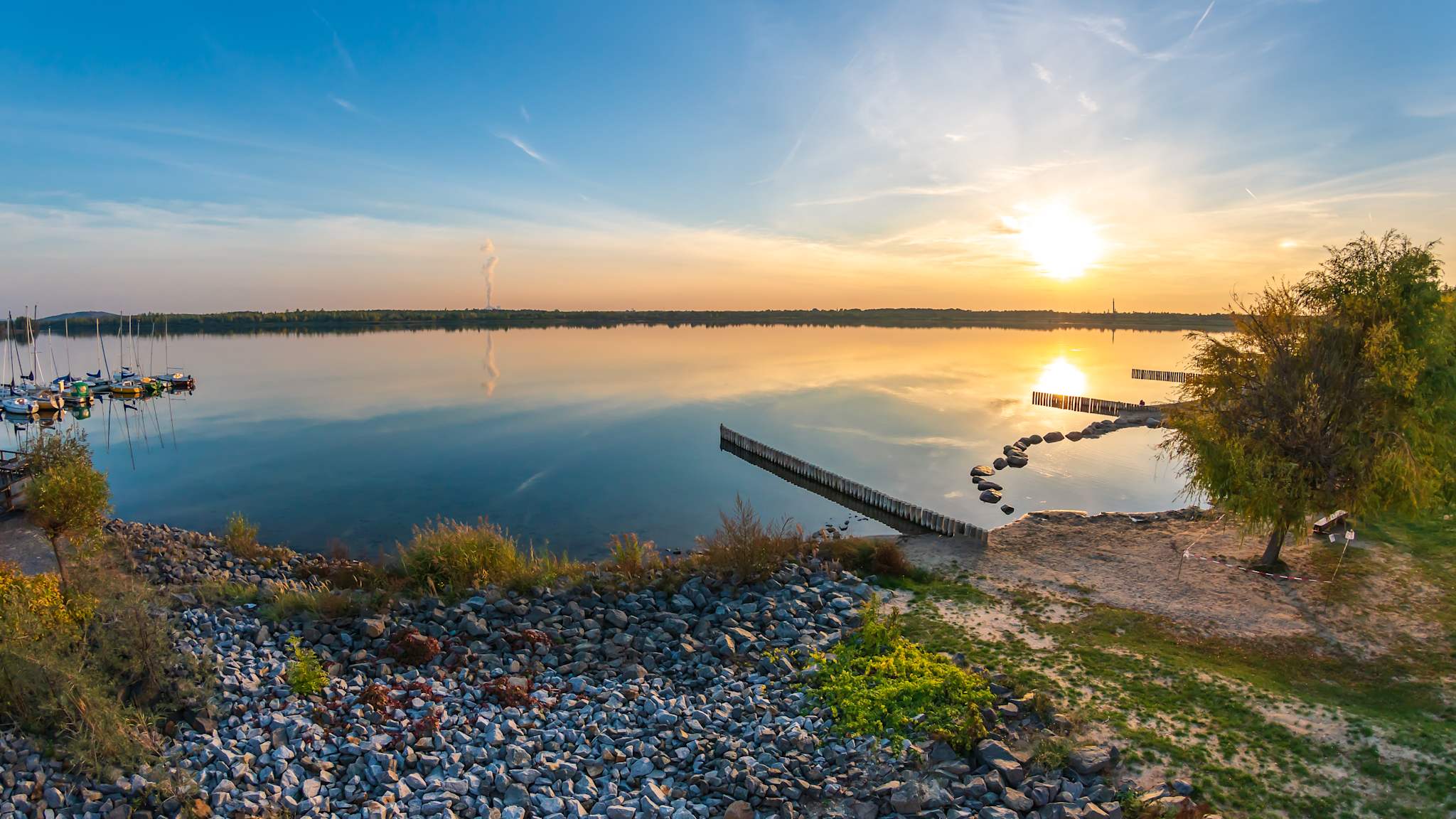 Ausblick auf Markkleeberger See mit Kies- und Sandstrand bei untergehender Sonne bei Leipzig.