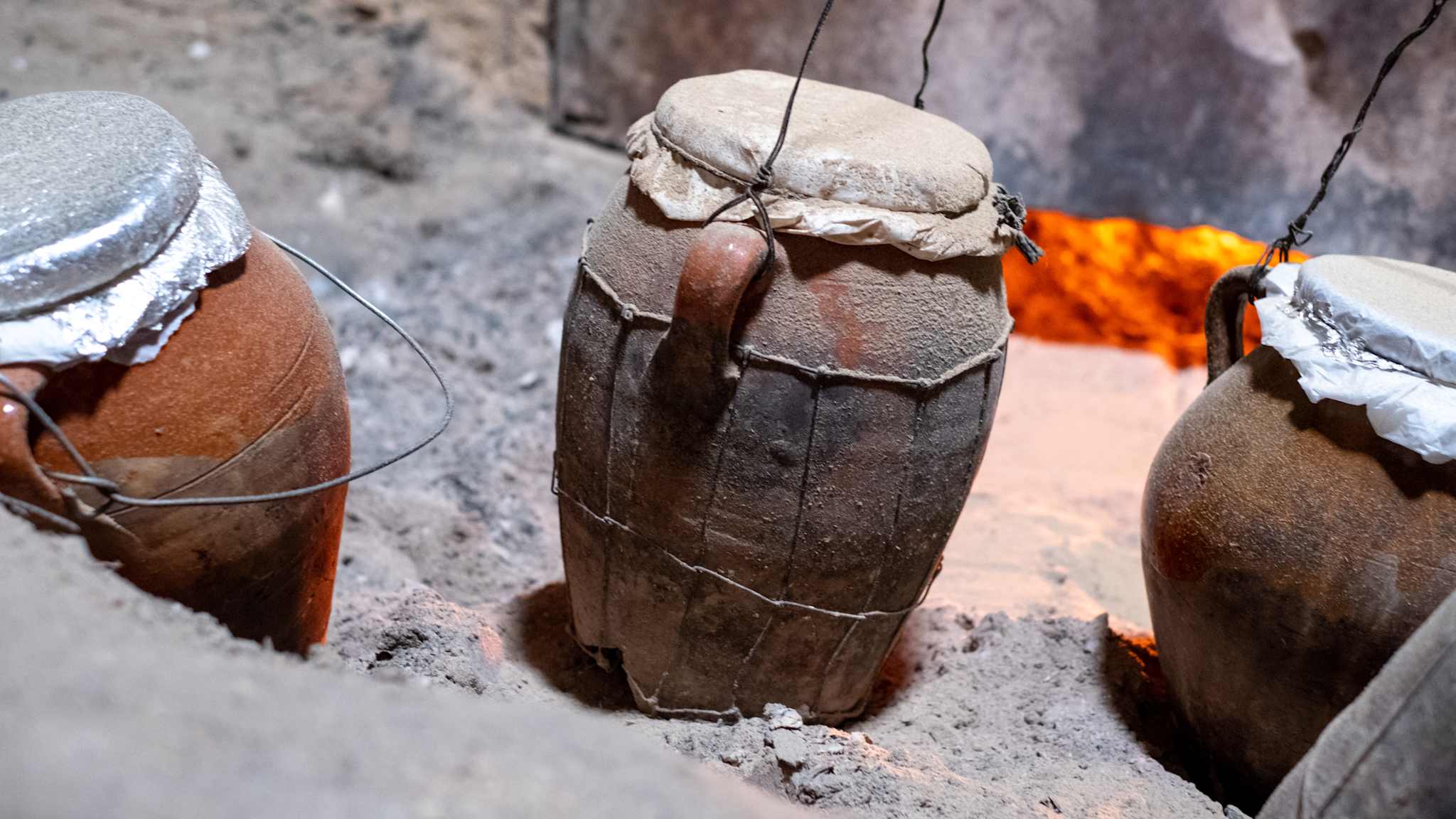 Tongefäße in Asche, Glut im Hintergrund