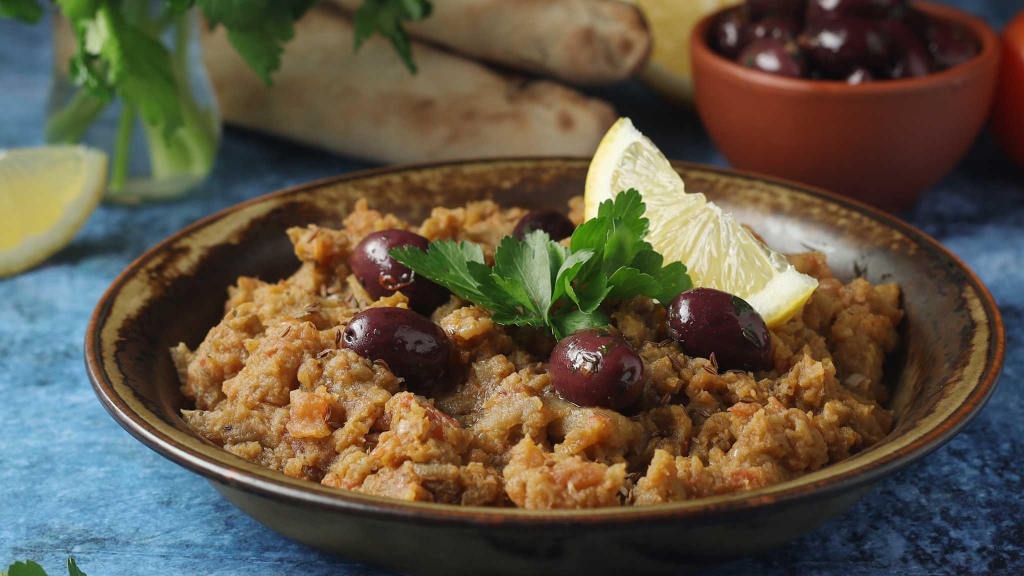 Schale mit Auberginen-Creme, garniert mit Oliven und Zitrone