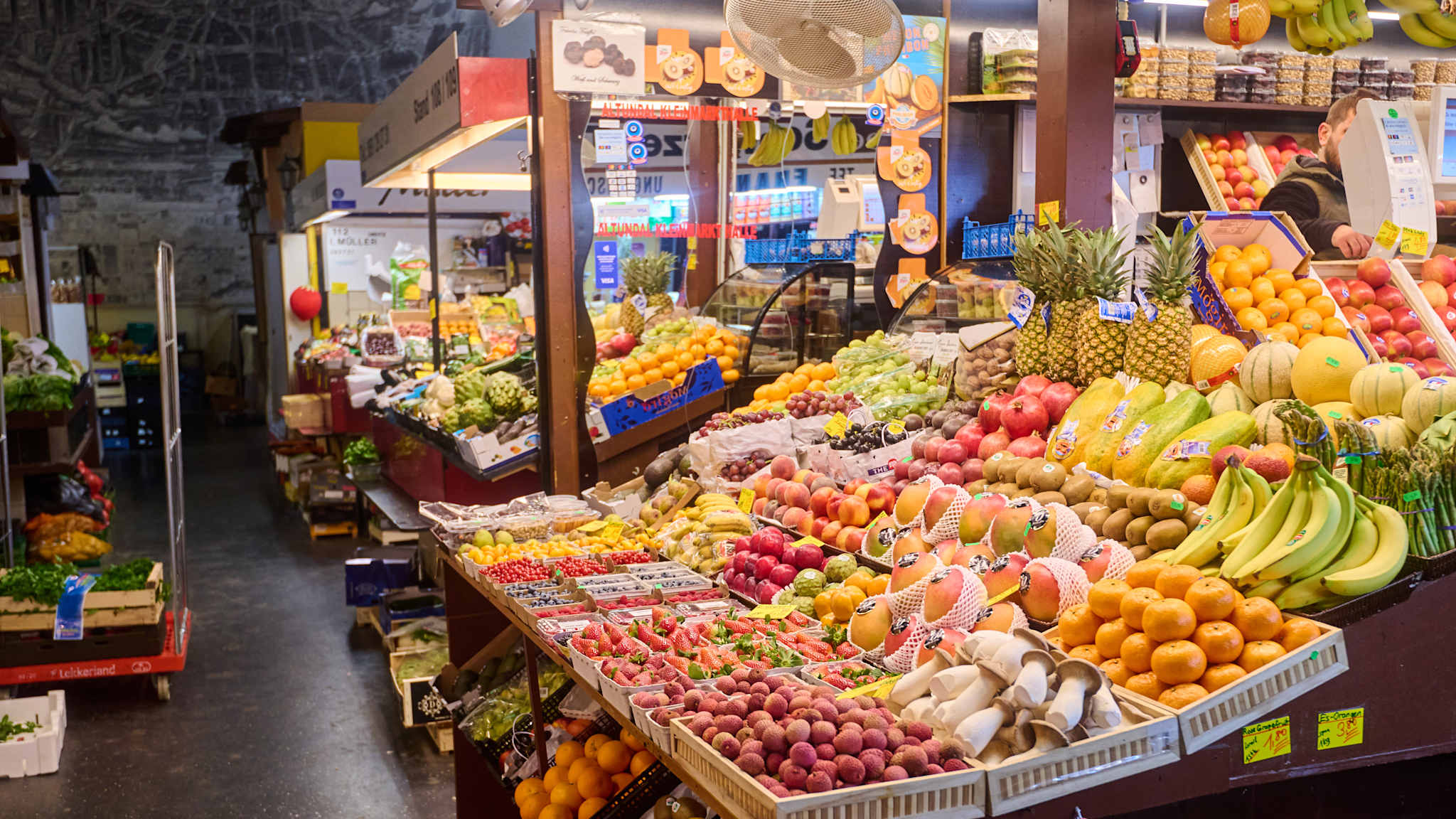 Marktstände mit Obst und Gemüse in einer Markthalle