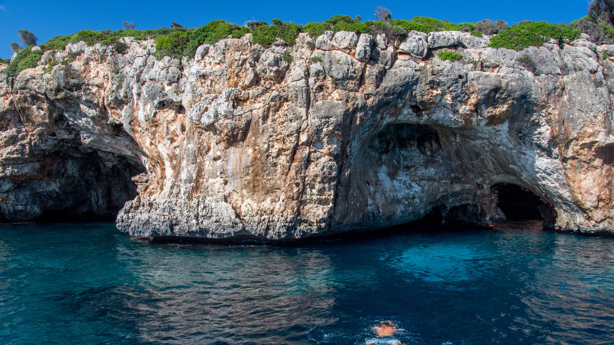 Person taucht zu einer Höhle an der Küste Mallorcas im Mittelmeer © iStock.com/Thomas Bernd