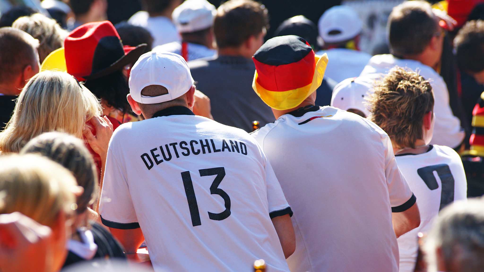 Fans in Deutschlandtrikots sitzen draußen beim Public Viewing