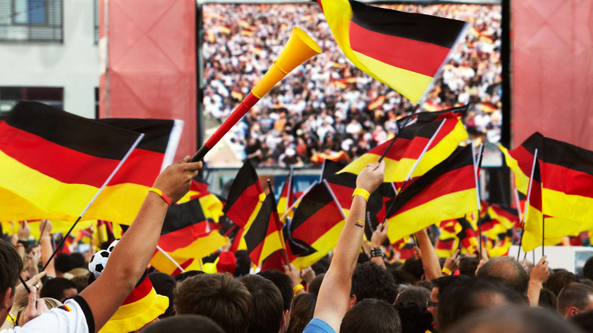 Fans mit Deutschlandflaggen vor einem großen Bildschirm
