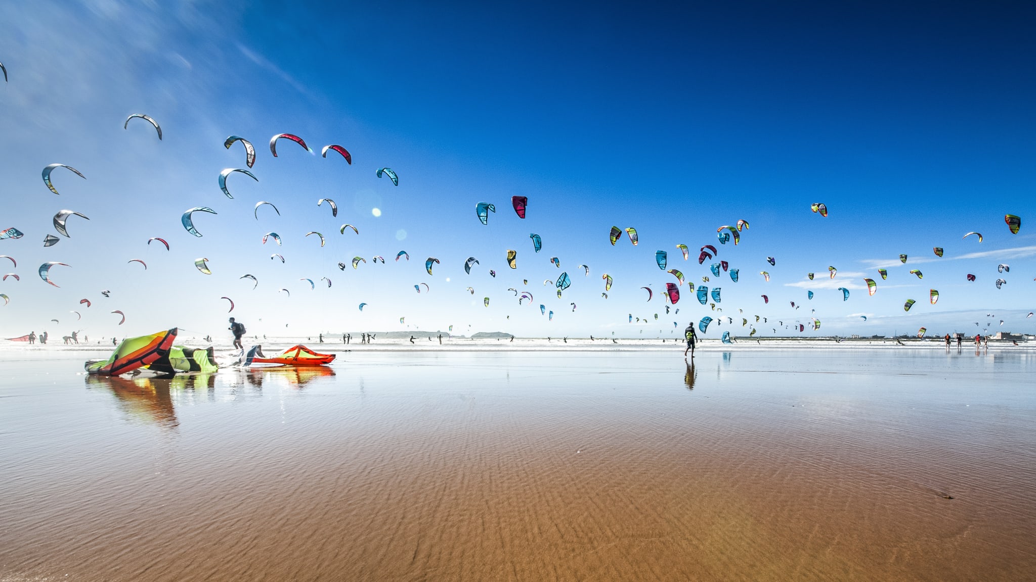 Riesige Menge von Kite- und Windsurfern an einem flachen Sandstrand in Marokko © iStock.com/Szymon Barylski