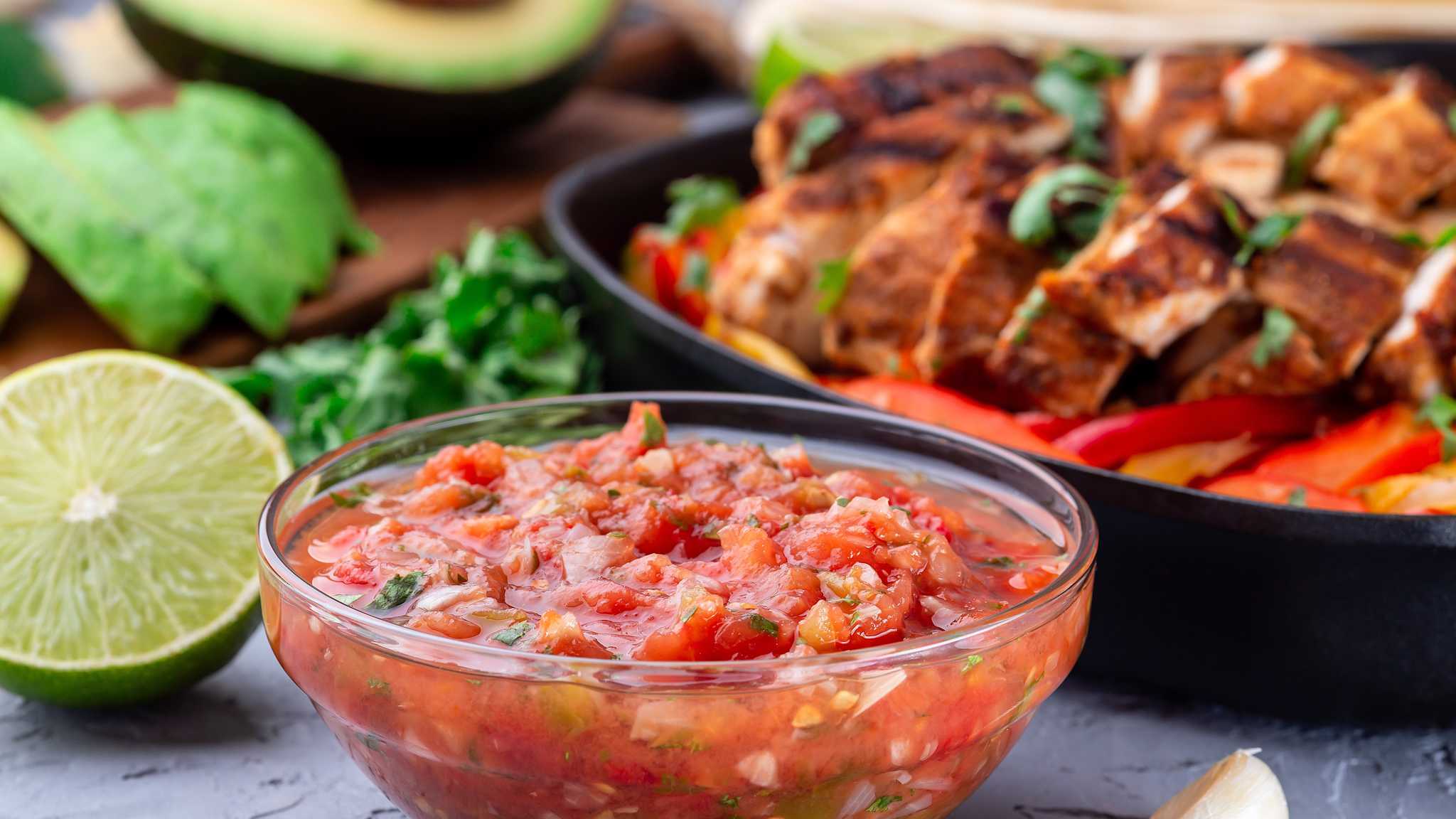 Glasschälchen mit Salsa, anderes Gericht unscharf im Hintergrund